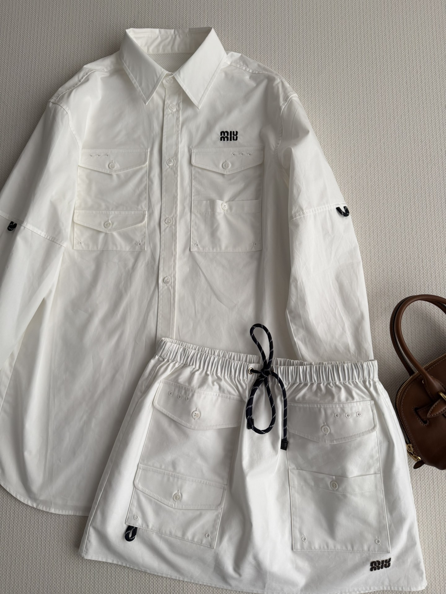 NO:734966,Miu Mi*26 early spring series white workwear skirt, made of crisp cotton poplin, A-line silhouette + multi-pocket design, practical and stylish!  The drawstring at the waist is adjustable and suitable for various body shapes. The mini letter logo on the side is highly recognizable. The white color is fresh and versatile.  Pair it with a sweater or short vest to easily switch between sweet and cool or hot girl style.  A must-have for going out in early spring!  It is suitable for daily wear or light exercise. It is comfortable and fashionable. It is the highlight of your early spring wardrobe!  SML,,miumiu,skirts,19860909Miu Mi*26早春系列白色工装半裙,采用挺括棉质府绸,A字廓形+多口袋设计,实用又有型！腰部抽绳可调节,适合各种身材,侧边迷你字母徽标超有辨识度.白色清新百搭．配针织衫或短款背心,轻松切换甜酷or辣妹风．早春出街必备！日常穿搭或轻运动都很OK,舒适又时髦,是早春衣橱亮点单品！SML,,miumiu,skirts,,Women's clothing