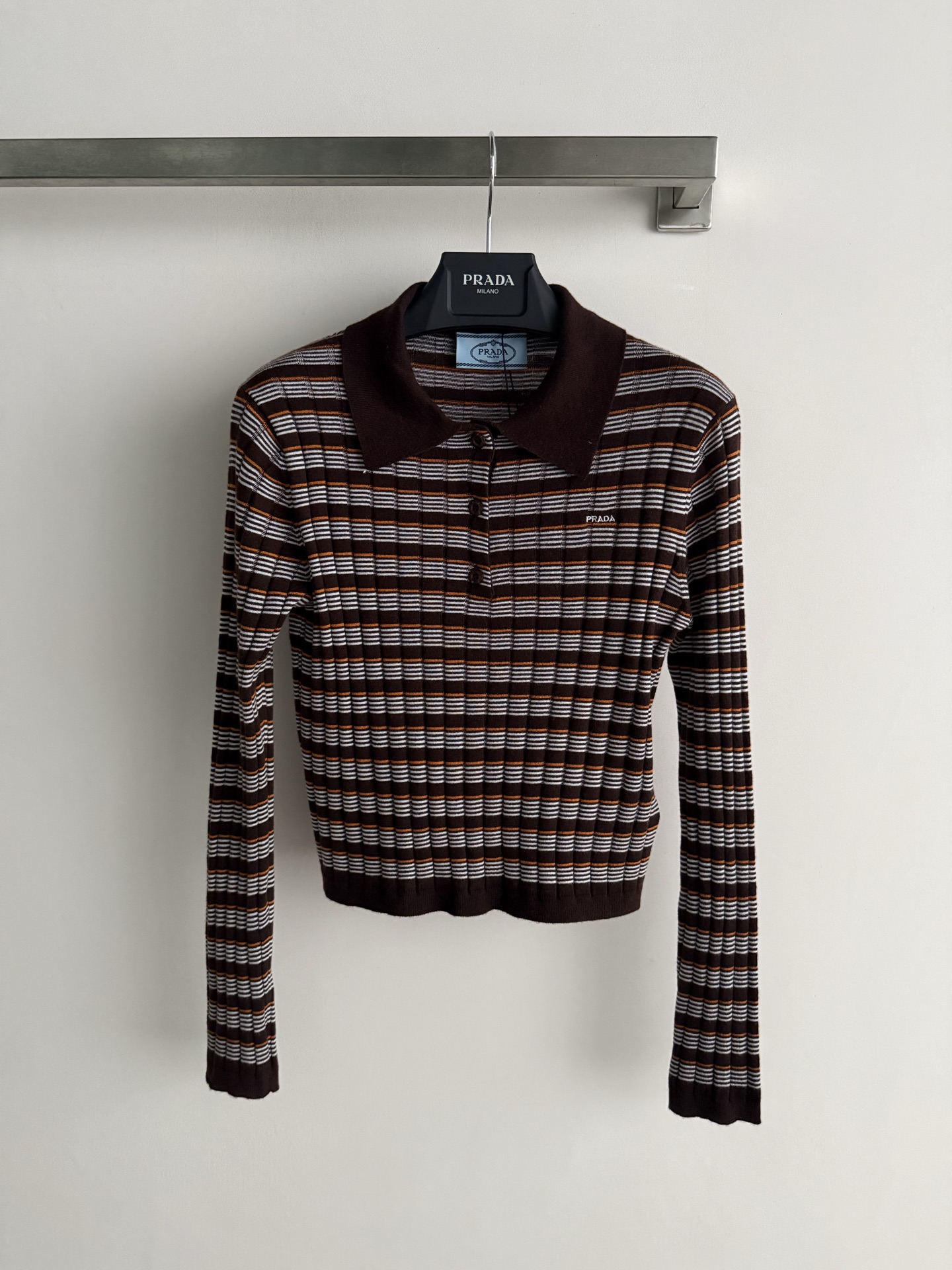 NO:931849,Prad*26 early autumn series short striped knitted Polo shirt, brown main tone + white stripes, full of retro college style!  The knitted fabric is soft and comfortable, and the long-sleeved design is perfect for autumn wear. The classic Polo collar + three-button placket, low-key printed logo on the chest, full of details. It can be easily controlled for daily commuting and leisure. Pair it with a skirt or jeans, and you can switch between literary or casual styles at will!  SML,,prada,skirts,jeans,19860909Prad*26初秋系列 短款条纹针织Polo衫,咖啡色主调+白色条纹,复古学院风满满！针织面料柔软舒适,长袖设计超适合秋季穿搭.经典Polo领+三颗纽扣开襟,胸前低调印花Logo,细节感拉满.日常通勤、休闲都能轻松驾驭,搭配半裙或牛仔裤,文艺or休闲风随心切换！SML,,prada,skirts,jeans,,Women's clothing