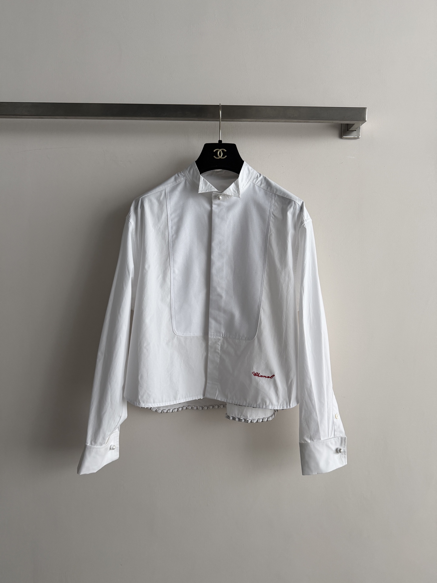 NO:951515,Chane*'s new white cotton short shirt. The front chest has a large veneer structure, and the red Chanel handwritten letters are embroidered in the lower right corner. A row of silver metal chains hangs from the hem, which is very designed, full of brand sense, and the version is loose, lazy and versatile. SML, Chanel-clothing, chanel, chanel, shirts,19860909Chane*新款白色棉质短款衬衫.前胸大贴面结构感,右下角红色Chanel手写字母刺绣.下摆垂一排银色金属链条,非常有设计,品牌感满满版型偏宽松,慵懒百搭.SML,香奈儿-服装,chanel,chanel,shirts,,Women's clothing