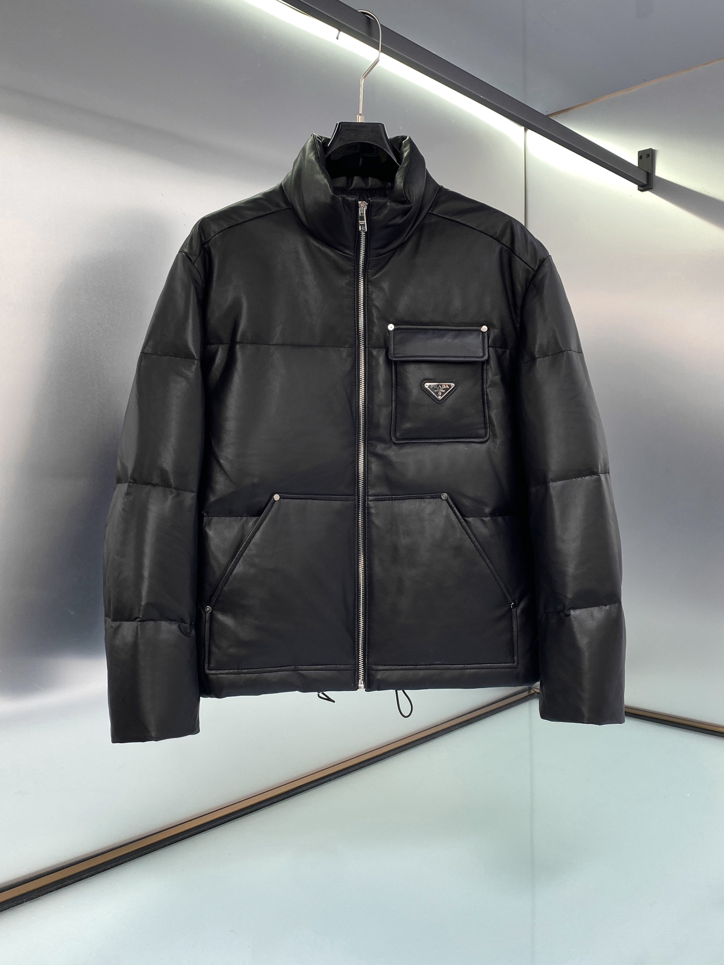 Prada, chaqueta bomber de plumón de piel de oveja con logo. La chaqueta corta de plumón de Re-Nylon utiliza material Re…