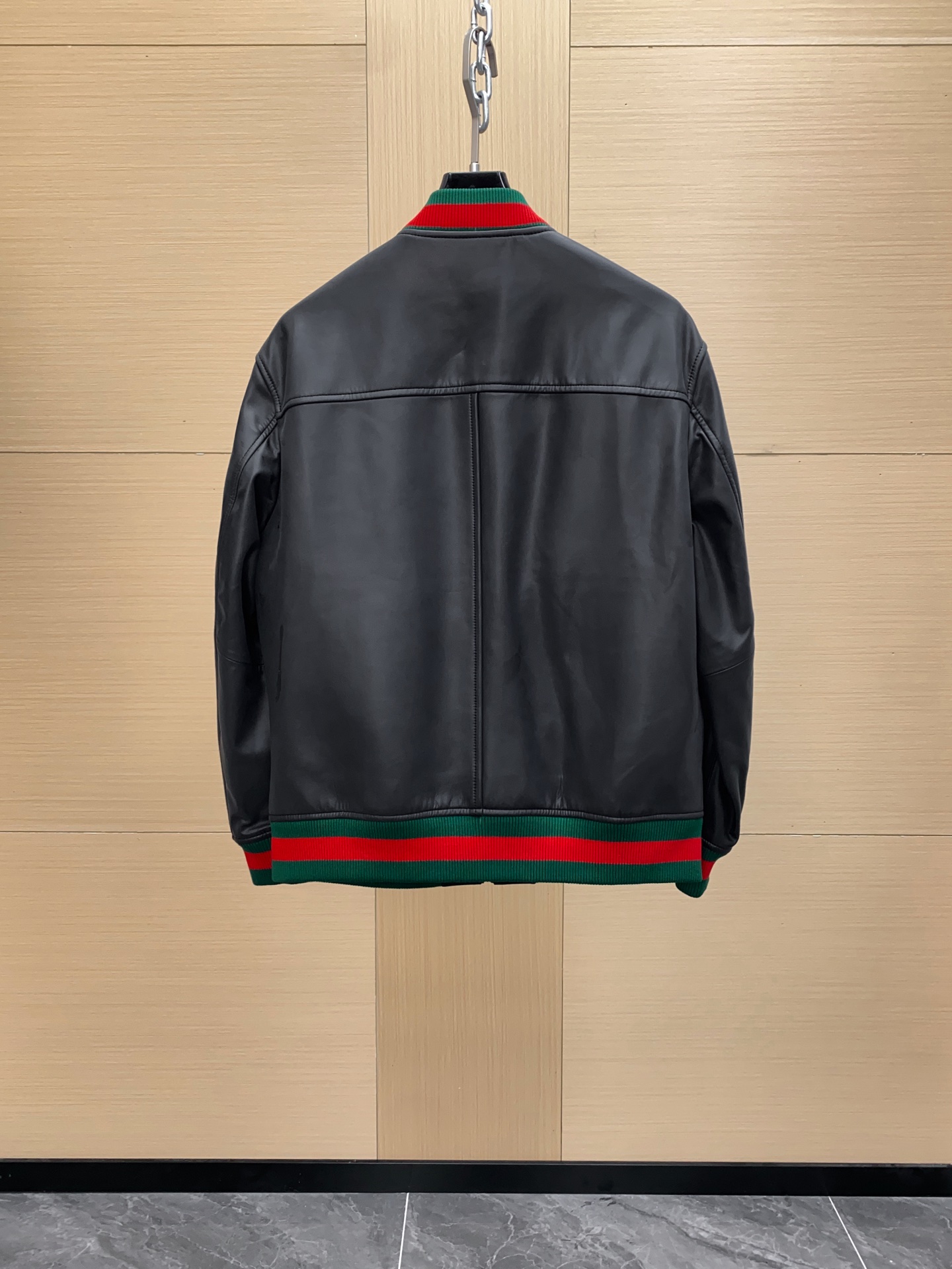 P1260 Gucci古驰纳帕皮飞行员夹克外套 。柔软纳帕皮革 + 羊毛棉混纺针织,质感与舒适度
外层选用柔软细腻的黑色纳帕羊皮,皮质纹理自然细腻,触感顺滑,兼具挺括感与柔韧度。表面光泽均匀,展现低调奢华的高级质感。 
针织拼接工艺 袖子与背部采用羊毛与棉混纺针织面料,针脚密实且富有弹性。在保持舒适穿着体验的同时,增强衣身的透气性与灵活性。立体剪裁版型直筒修身飞行员夹克版型,肩线挺括,身形利落。拼接工艺自然过渡 兼顾运动风与都市感。
门襟配备金属拉链,顺滑耐用。 袖口与下摆采用罗纹针织,并点缀 经典红绿织带,彰显标志性元素。 内里采用光滑里布拼接针织,穿着顺滑舒适。增添保暖性与耐穿性。