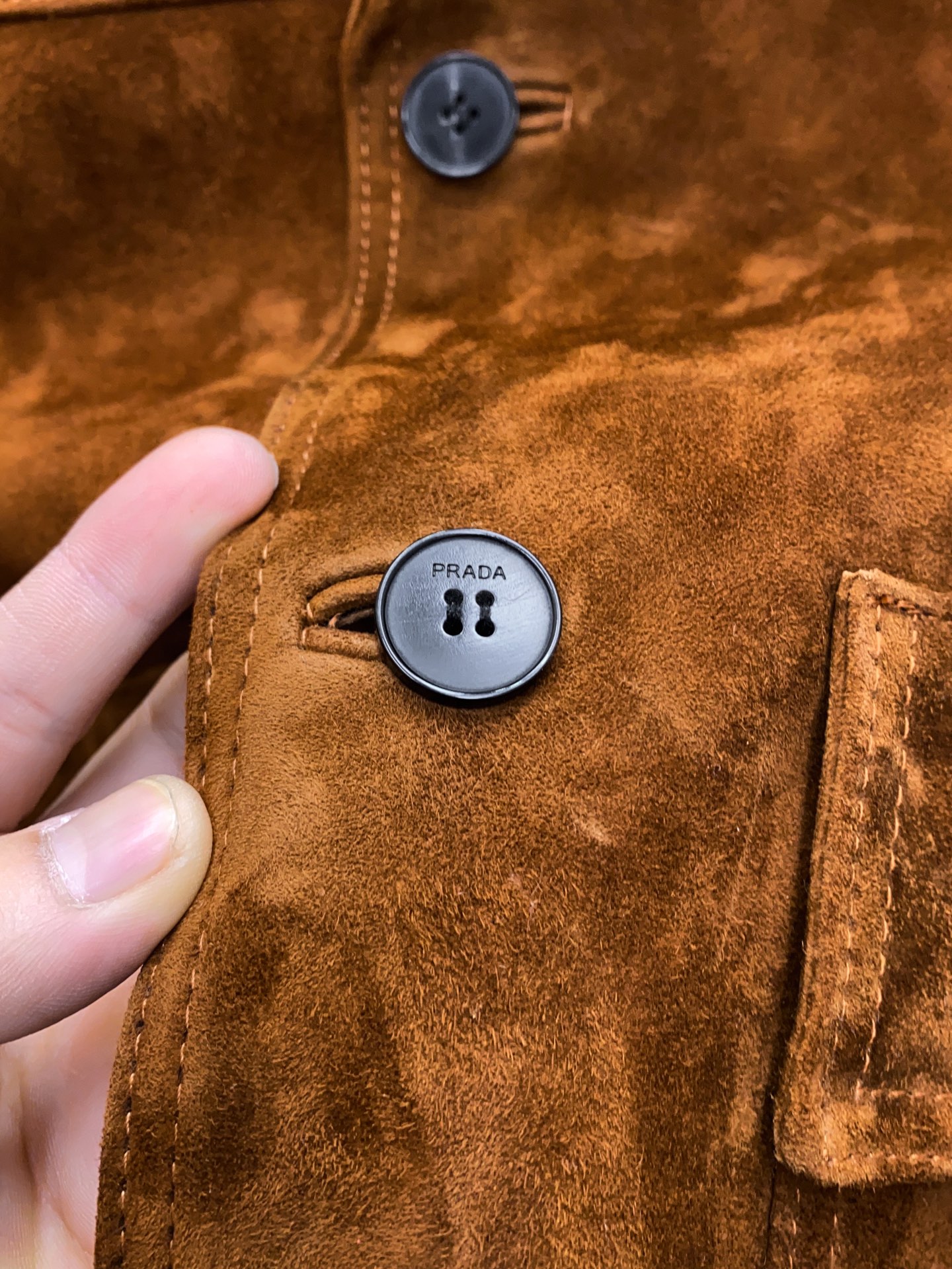 P1660 🖤Prada这款咖色麂皮绒面夹克， 采用南非混种小羊皮！质感高级又低调，复古品牌刻字牛角扣+明线细节，立体感满满✨。多口袋设计，实用又有型，箱型廓形剪裁，商务or休闲都能轻松驾驭。丝绒面料硬挺，秋冬穿超有氛围感，搭配西装裤或牛仔裤都很出彩！通勤、日常、轻正式场合都能hold住，是2025春夏热门单品之一～尺码：48-56