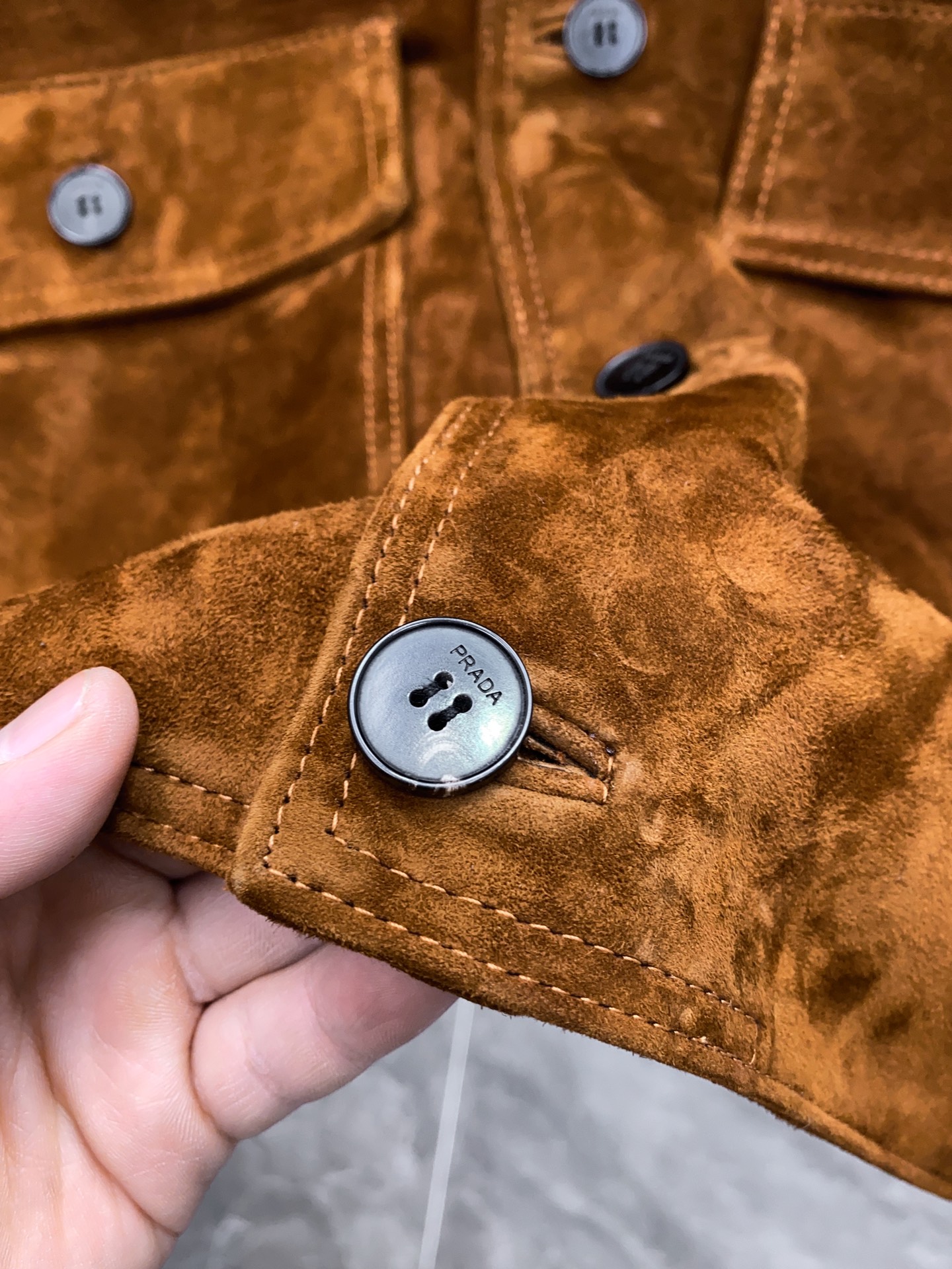 P1660 🖤Prada这款咖色麂皮绒面夹克， 采用南非混种小羊皮！质感高级又低调，复古品牌刻字牛角扣+明线细节，立体感满满✨。多口袋设计，实用又有型，箱型廓形剪裁，商务or休闲都能轻松驾驭。丝绒面料硬挺，秋冬穿超有氛围感，搭配西装裤或牛仔裤都很出彩！通勤、日常、轻正式场合都能hold住，是2025春夏热门单品之一～尺码：48-56