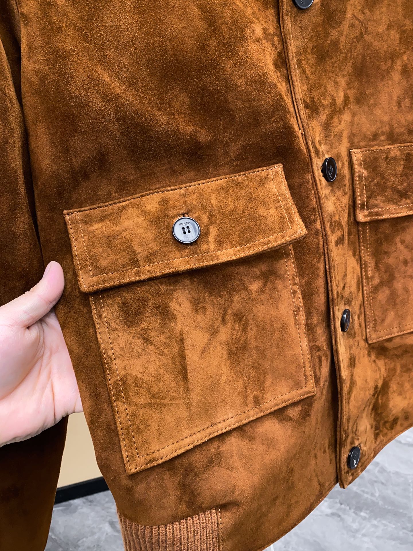 P1660 🖤Prada这款咖色麂皮绒面夹克， 采用南非混种小羊皮！质感高级又低调，复古品牌刻字牛角扣+明线细节，立体感满满✨。多口袋设计，实用又有型，箱型廓形剪裁，商务or休闲都能轻松驾驭。丝绒面料硬挺，秋冬穿超有氛围感，搭配西装裤或牛仔裤都很出彩！通勤、日常、轻正式场合都能hold住，是2025春夏热门单品之一～尺码：48-56