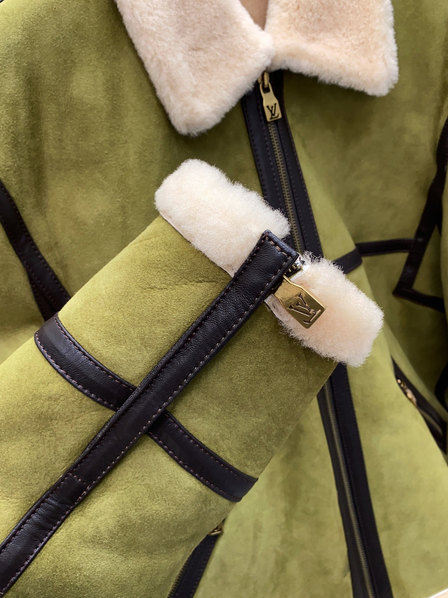 P2860 现货发售！LV 菲董操刀设计墨绿色麂皮羊羔毛皮毛一体外套夹克  本款 Bombardier 夹克取材舒软羊毛皮革，令后部饰钉描绘 2024 春夏秀场的LV Lovers 标识。柔暖绵羊毛内衬和衣领塑造经典男装廓形，大理石纹绒面外层呈现细腻肌理。撞色皮革饰带再添利落笔触。 标准版型 后部LV Lovers 标识点缀饰钉 尺码：48-56 