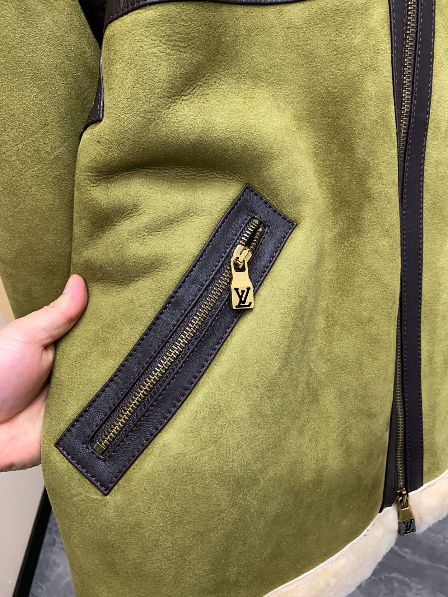 P2860 现货发售！LV 菲董操刀设计墨绿色麂皮羊羔毛皮毛一体外套夹克  本款 Bombardier 夹克取材舒软羊毛皮革，令后部饰钉描绘 2024 春夏秀场的LV Lovers 标识。柔暖绵羊毛内衬和衣领塑造经典男装廓形，大理石纹绒面外层呈现细腻肌理。撞色皮革饰带再添利落笔触。 标准版型 后部LV Lovers 标识点缀饰钉 尺码：48-56 