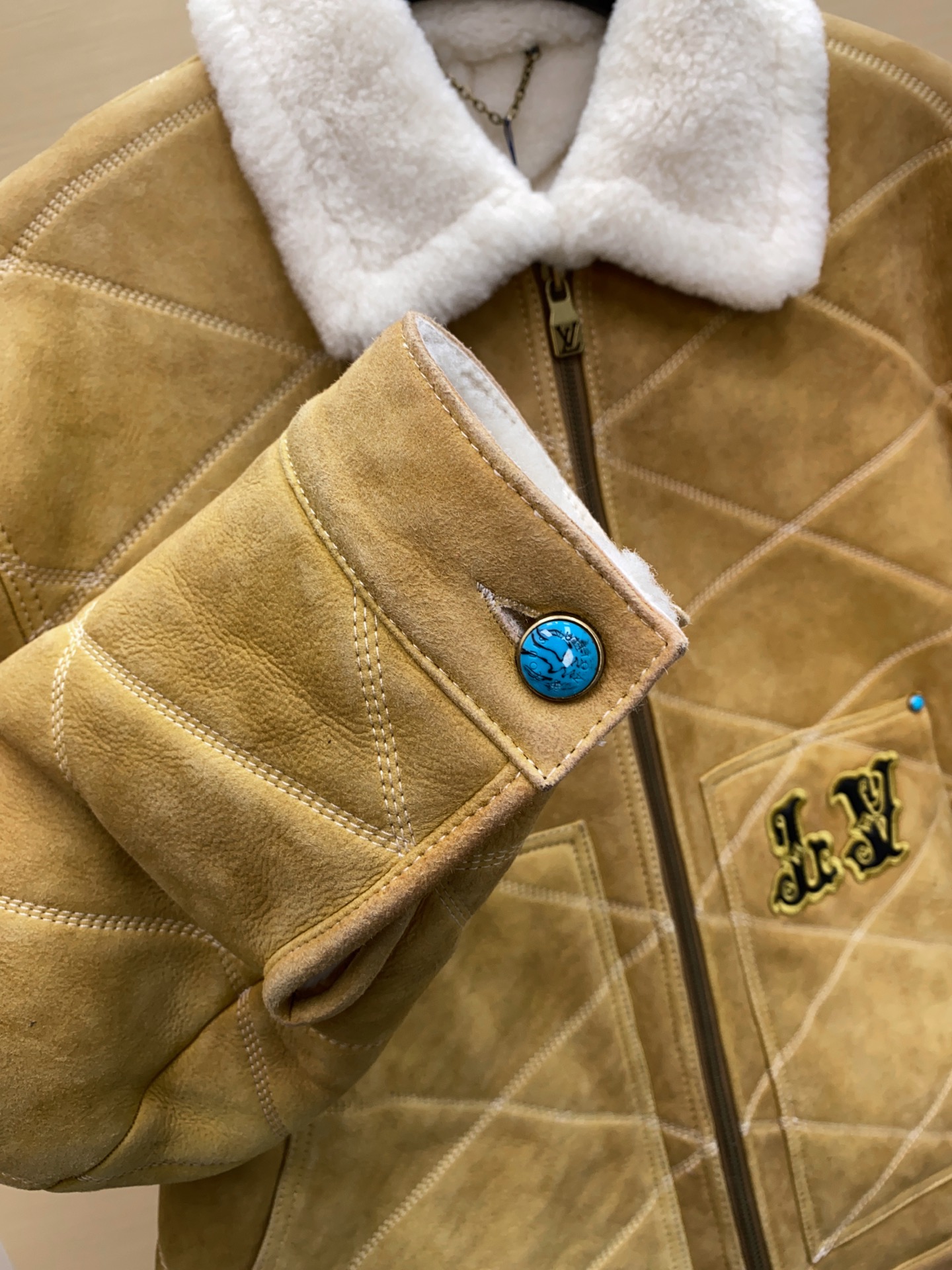 P2760 现货发售！LV 男装刺绣（羊皮毛一体）工装束腰夹克 本款羊毛皮革束腰夹克采用精湛匠艺构筑休闲廓形，以全幅菱格缝线致敬品牌传统硬箱的内衬设计。前后点缀复古加衬刺绣皮革 LV 和路易威登贴饰，点明 2025 秋冬秀场的 Far West 主题，纽扣和铆钉再添考究气息。
休闲版型 正面左侧口袋呈现加衬刺绣 LV 贴饰 后部呈现加衬刺绣路易威登贴饰 羊毛皮革衣领和内里 拉链前襟配有 LV 铭纹拉链头 纽扣和铆钉 尺码：48-56 