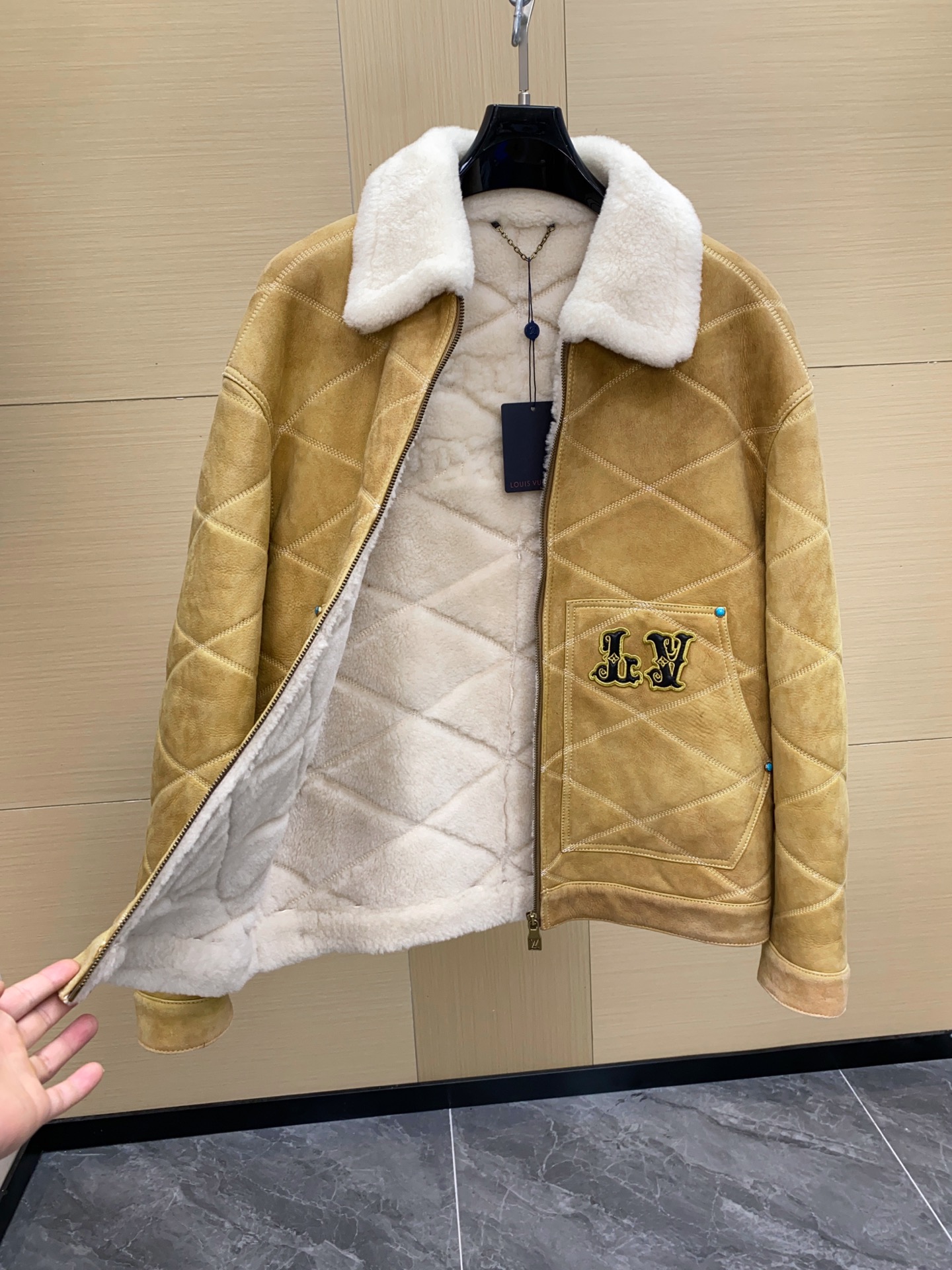 P2760 现货发售！LV 男装刺绣（羊皮毛一体）工装束腰夹克 本款羊毛皮革束腰夹克采用精湛匠艺构筑休闲廓形，以全幅菱格缝线致敬品牌传统硬箱的内衬设计。前后点缀复古加衬刺绣皮革 LV 和路易威登贴饰，点明 2025 秋冬秀场的 Far West 主题，纽扣和铆钉再添考究气息。
休闲版型 正面左侧口袋呈现加衬刺绣 LV 贴饰 后部呈现加衬刺绣路易威登贴饰 羊毛皮革衣领和内里 拉链前襟配有 LV 铭纹拉链头 纽扣和铆钉 尺码：48-56 