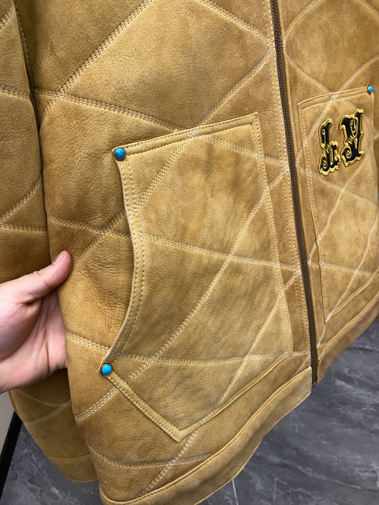 P2760 现货发售！LV 男装刺绣（羊皮毛一体）工装束腰夹克 本款羊毛皮革束腰夹克采用精湛匠艺构筑休闲廓形，以全幅菱格缝线致敬品牌传统硬箱的内衬设计。前后点缀复古加衬刺绣皮革 LV 和路易威登贴饰，点明 2025 秋冬秀场的 Far West 主题，纽扣和铆钉再添考究气息。
休闲版型 正面左侧口袋呈现加衬刺绣 LV 贴饰 后部呈现加衬刺绣路易威登贴饰 羊毛皮革衣领和内里 拉链前襟配有 LV 铭纹拉链头 纽扣和铆钉 尺码：48-56 