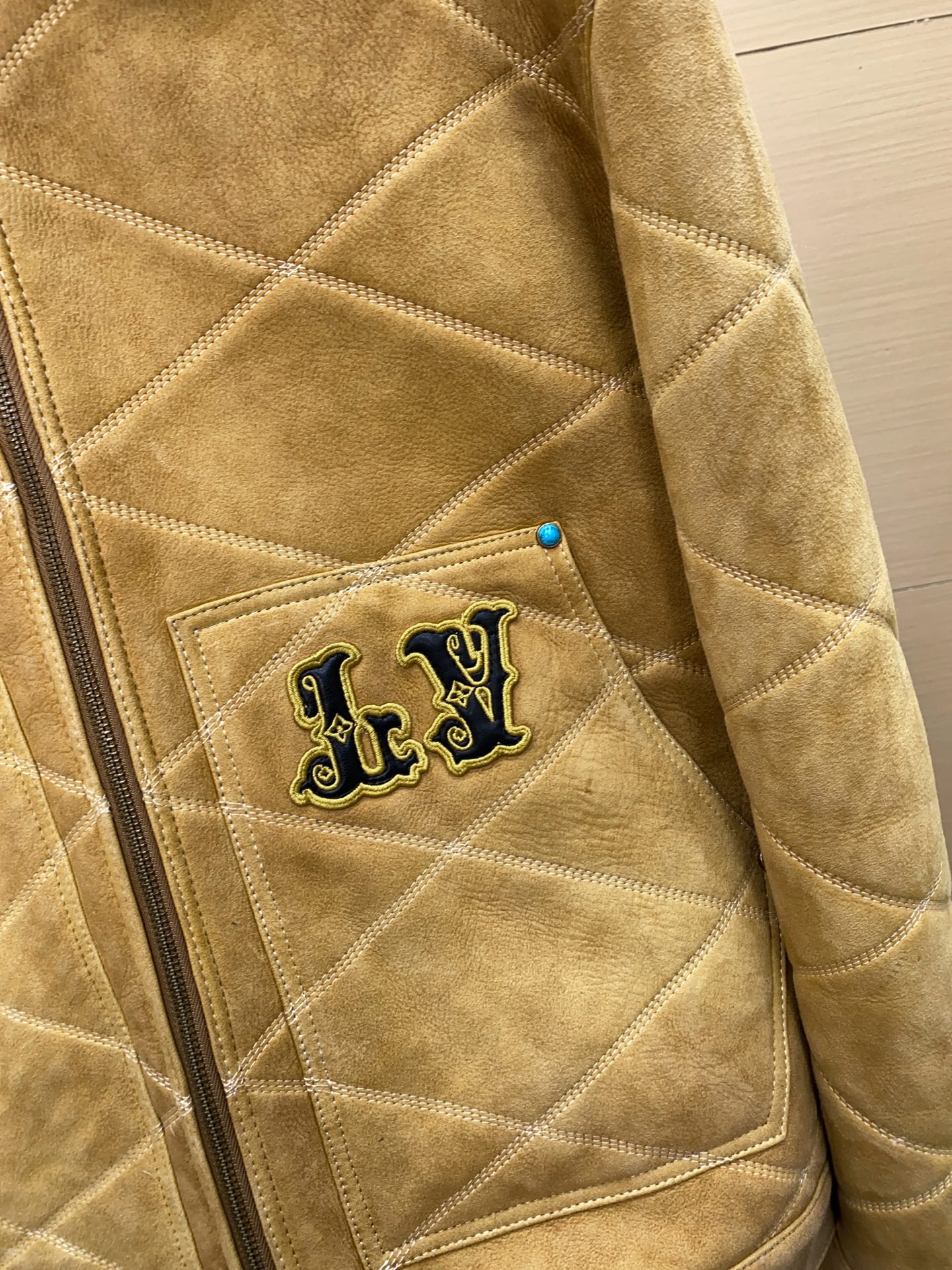 P2760 现货发售！LV 男装刺绣（羊皮毛一体）工装束腰夹克 本款羊毛皮革束腰夹克采用精湛匠艺构筑休闲廓形，以全幅菱格缝线致敬品牌传统硬箱的内衬设计。前后点缀复古加衬刺绣皮革 LV 和路易威登贴饰，点明 2025 秋冬秀场的 Far West 主题，纽扣和铆钉再添考究气息。
休闲版型 正面左侧口袋呈现加衬刺绣 LV 贴饰 后部呈现加衬刺绣路易威登贴饰 羊毛皮革衣领和内里 拉链前襟配有 LV 铭纹拉链头 纽扣和铆钉 尺码：48-56 