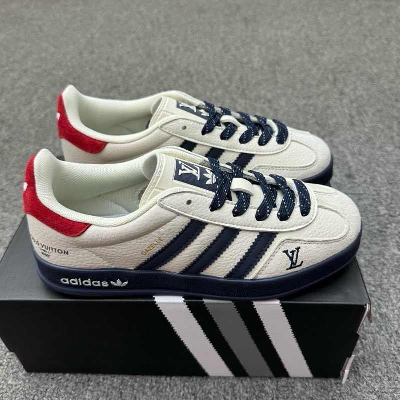 🈴特价福利🉐💰280（36-45半） 公司级 头层 ［定制球鞋］ Louis Vuitton x Adidas Original Gazelle Indoor 路易威登LV x 阿迪达斯 低帮 联名灰白蓝 桑巴防滑耐磨轻便低邦板鞋男女同款 鞋身整体采用米白色皮革打造，搭配经典T字形灰色麂皮框架覆盖层，鞋身两侧经典锯齿三条杠Logo采用蓝色点缀，侧身点缀金色Gazelle字样，鞋舌上以白色LV字样及Adidas品牌Logo呈现，瞬间提升鞋子的时尚程度，后跟装饰片辅以红色制作并带有白色三叶草LLogo，后跟印有Louis Vuitton字样，彰显联名身份；最后以蓝色中底搭配同色橡胶外底完善整体设计收尾。 货号：DM1234-002/3/6/7/9/11 尺码：36-45带半码