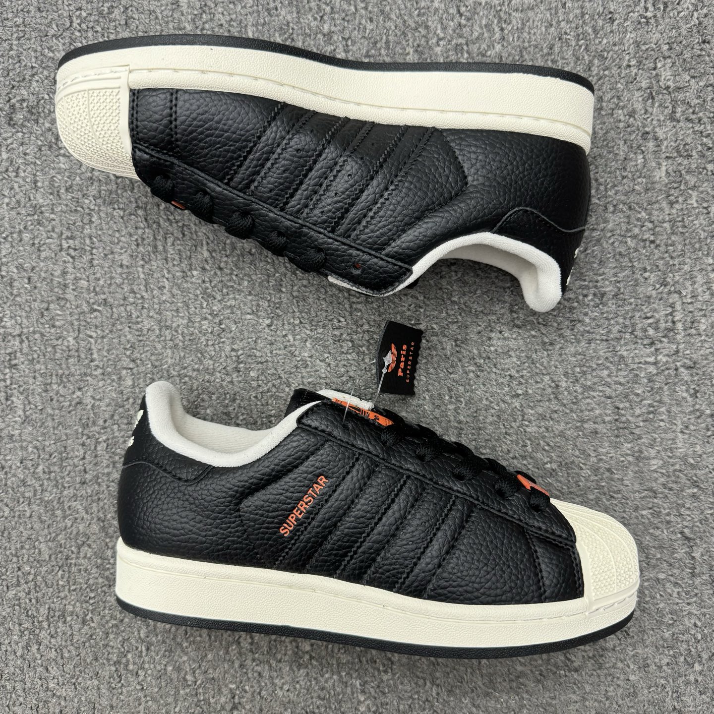 【💰💰110】（35.5-45半）
Adidas Original Superstar 2 "Paris" 阿迪达斯 低帮 巴黎联名 黑橙 男女同款 贝壳头2代防滑耐磨轻便低邦板鞋 鞋身整体以黑色皮革打造，搭配经典白色贝壳头，鞋身两侧经典锯齿三条杠Logo采用黑色点缀，侧身Superstar字样橙色压印妆点，鞋舌橙色底色上以三叶草Logo及Paris字样呈现，瞬间提升鞋子的时尚程度，后跟装饰片辅以黑色皮革制作并带有白色三叶草Logo及Paris字样，外加法国75数字的鞋带饰品致敬巴黎区号，最后以白色中底搭配生胶色橡胶外底完善整体设计收尾。
货号：JQ3223
尺码：35¹/₃ 36 36²/₃ 37¹/₃ 38 38²/₃ 39¹/₃ 40 40²/₃ 41¹/₃ 42 42²/₃ 43¹/₃ 44 44²/₃ 45¹/₃