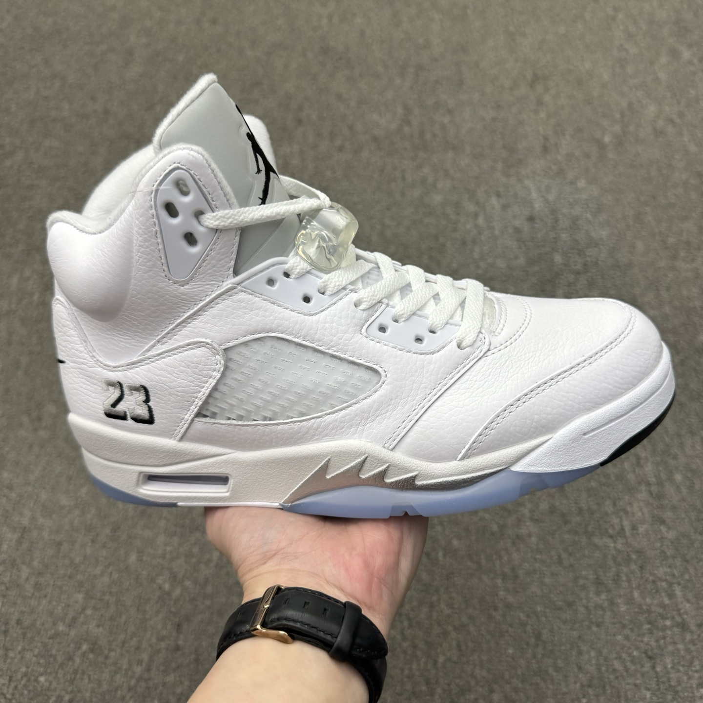 5半) 纯原版本 Air Jordan 5 Retro "Metallic White" 高帮 复刻白银 AJ5 乔丹5代 aj5 乔5 高邦 复刻白银 乔丹篮球鞋系列 鞋面整体采用了皮革面料打造,配色方面以白色示人,整体颜值还是非常不错的!鞋身侧面的透气网格使用白色呈现,中底部分的锯齿元素则采用银色点缀,鞋舌部分依旧保留标志性的3M反光设计呈现,并且带有黑色Jumpman Logos点缀,此外后跟部分带有"23"字样刺绣,代表着乔丹的传奇号码,是对经典的致敬与传承,表明鞋款身份.中底可视Max Sole气垫,后跟Nike Air标识采用黑色刺绣点缀,与鞋舌相呼应.鞋底使用白色中底搭配冰蓝透明水晶橡胶大底呈现,水晶大底下印有黑色Jfumpman Logo,为整个设计收尾. 货号:HQ7978-103(2026.06.01发售)