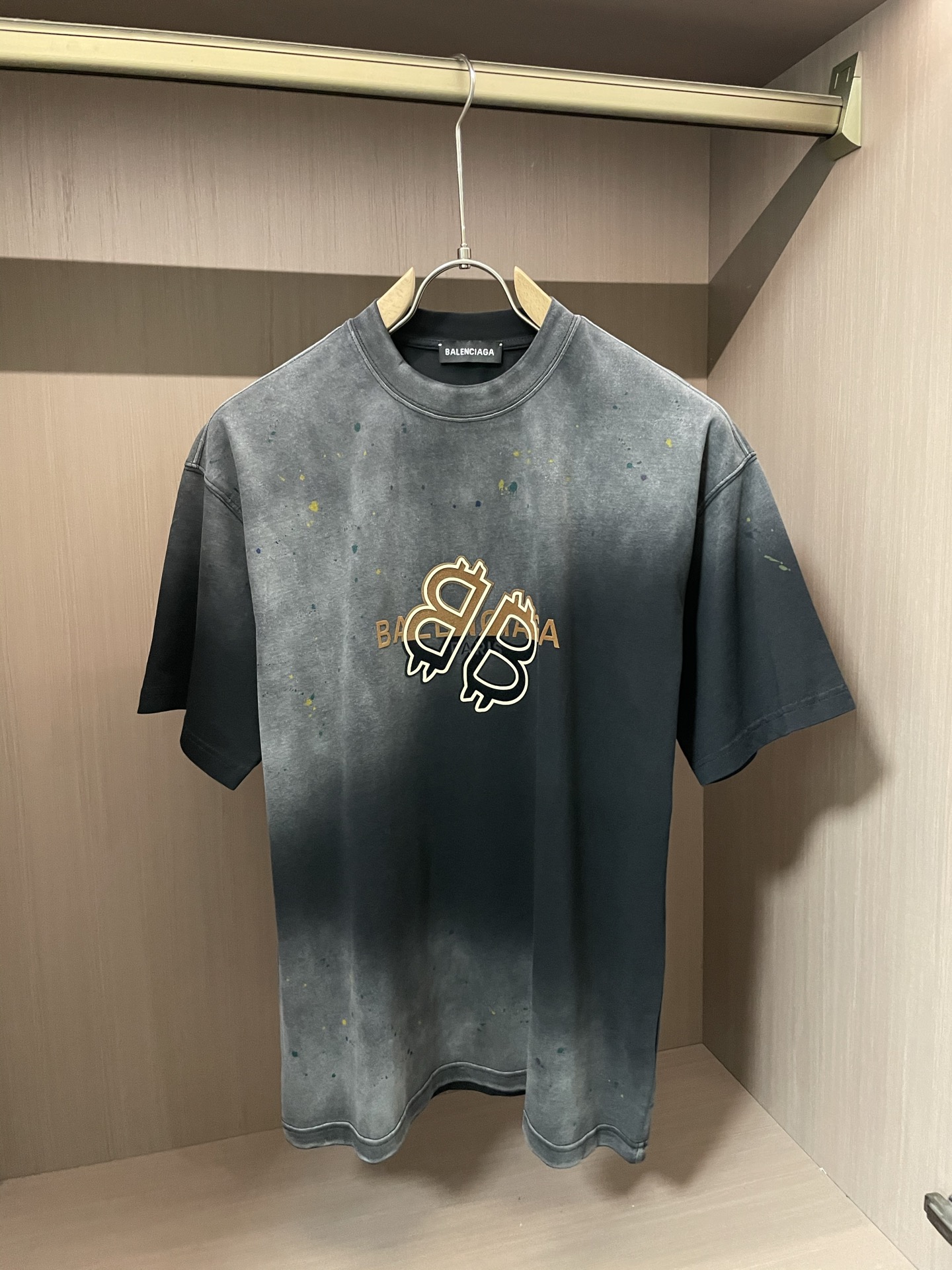 
巴黎世家 做旧渐变 T 恤，灰黑过渡带泼墨感，金色比特币字母标超吸睛。宽松版型，街头潮流感拉满，日常搭