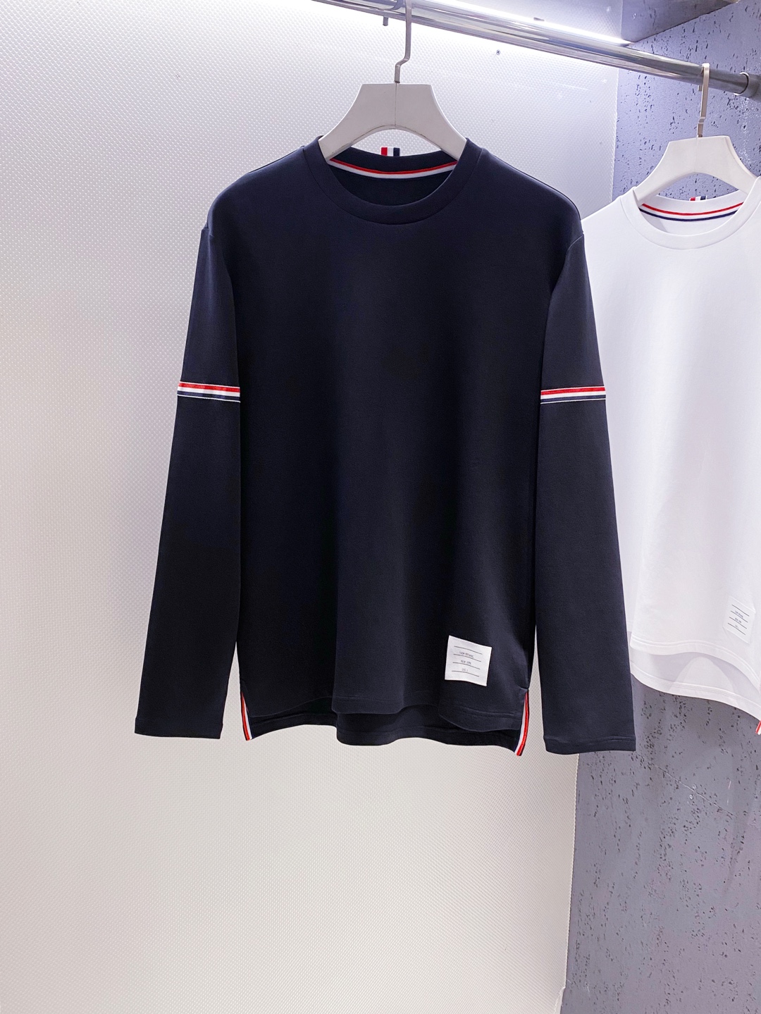 TB~袖臂经典织带嵌花薄太空棉长袖T恤衫
秋冬新款
ThomB&hellip;太空薄棉长袖T恤、解锁先锋穿搭密码.. 将经典与创新融合，用细节诠释品质，邀你共赴这场时尚之约，解锁独属于你的潮流穿搭。
袖臂处经典织带标识嵌花，红白蓝三色交织，是Thom Br..标志性元素，以精湛工艺融入衣物，如同品牌名片，举手投足间彰显独特品味，是低调中的高调宣言 ，无论是日常出街还是社交场合，都能让你成为目光焦点。
匠心剪裁，设计感拉满。前短后长的衣摆设计，打破常规，塑造出独特的层次感，行走间衣角轻扬，尽显灵动与随性；下摆两侧开叉处同样点缀织带，为整体造型增添细节亮点，更在不经意间流露精致态度，轻松提升穿搭的时髦指数 。
选用太空薄棉面料，奢护每寸肌肤，轻盈似云朵，贴肤感满分，透气性绝佳，能保持清爽。细密的纺织工艺，让面料柔软又有韧性，耐穿且不易变形，为你带来持久的舒适体验。是休闲潮流时尚的首选之一。

颜色：白色、黑色
规格：S--XXL
    P210
M码:肩宽45.胸围106. 前衣长66. 后衣长71.袖长62
L码：肩宽46.胸围110.前衣长67.后衣长72.袖长63