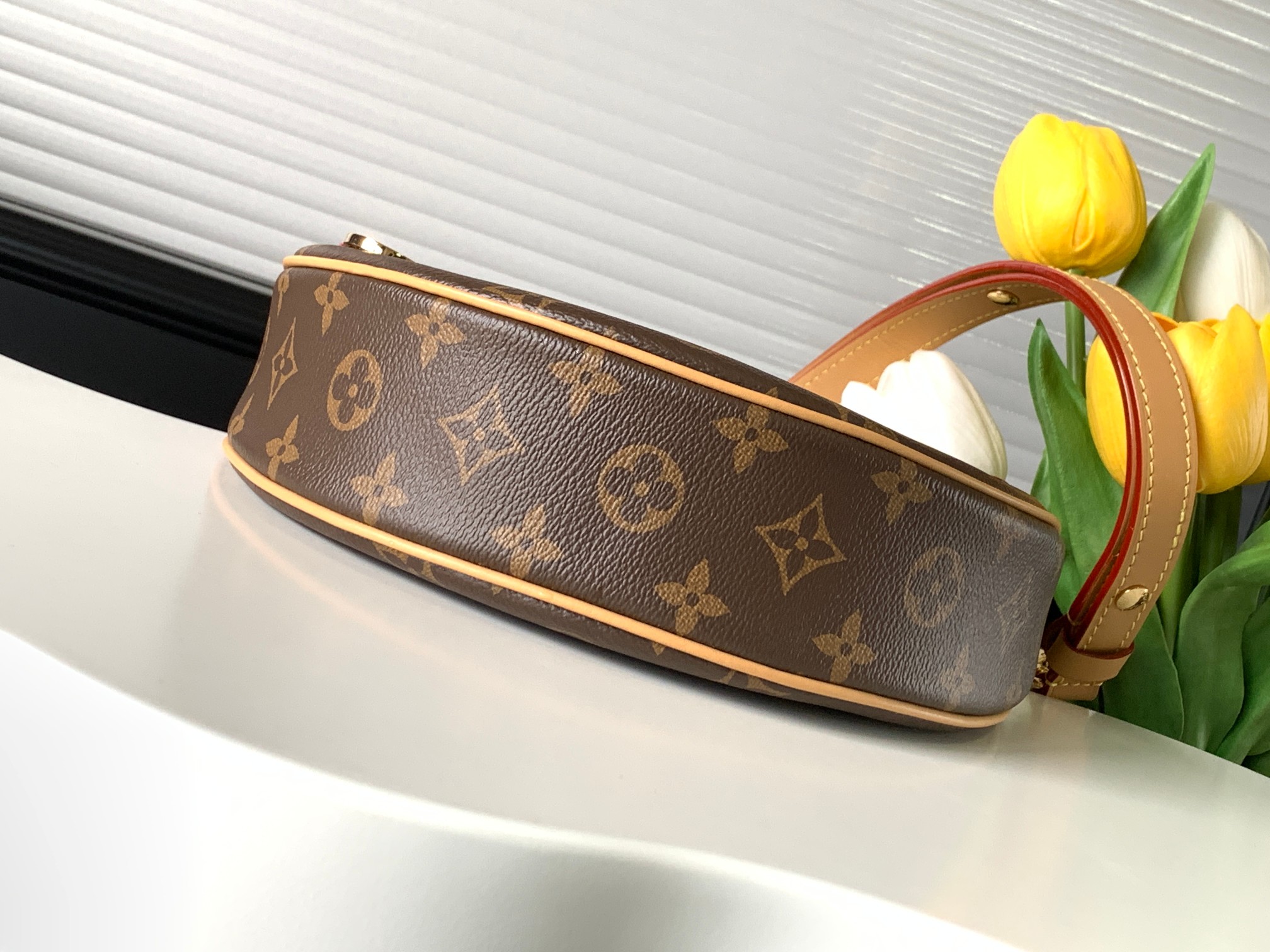 M81098 Nicolas Ghesquière 溯源档案中的 Croissant 手袋，于 2022 早春系列推出 Loop 半月形法棍包。紧凑构型贴合身体律动，拉链前袋配有圆形拉链头，链条和皮革肩带实现肩背和斜挎选择。尺寸：23 x 13 x 6 厘米