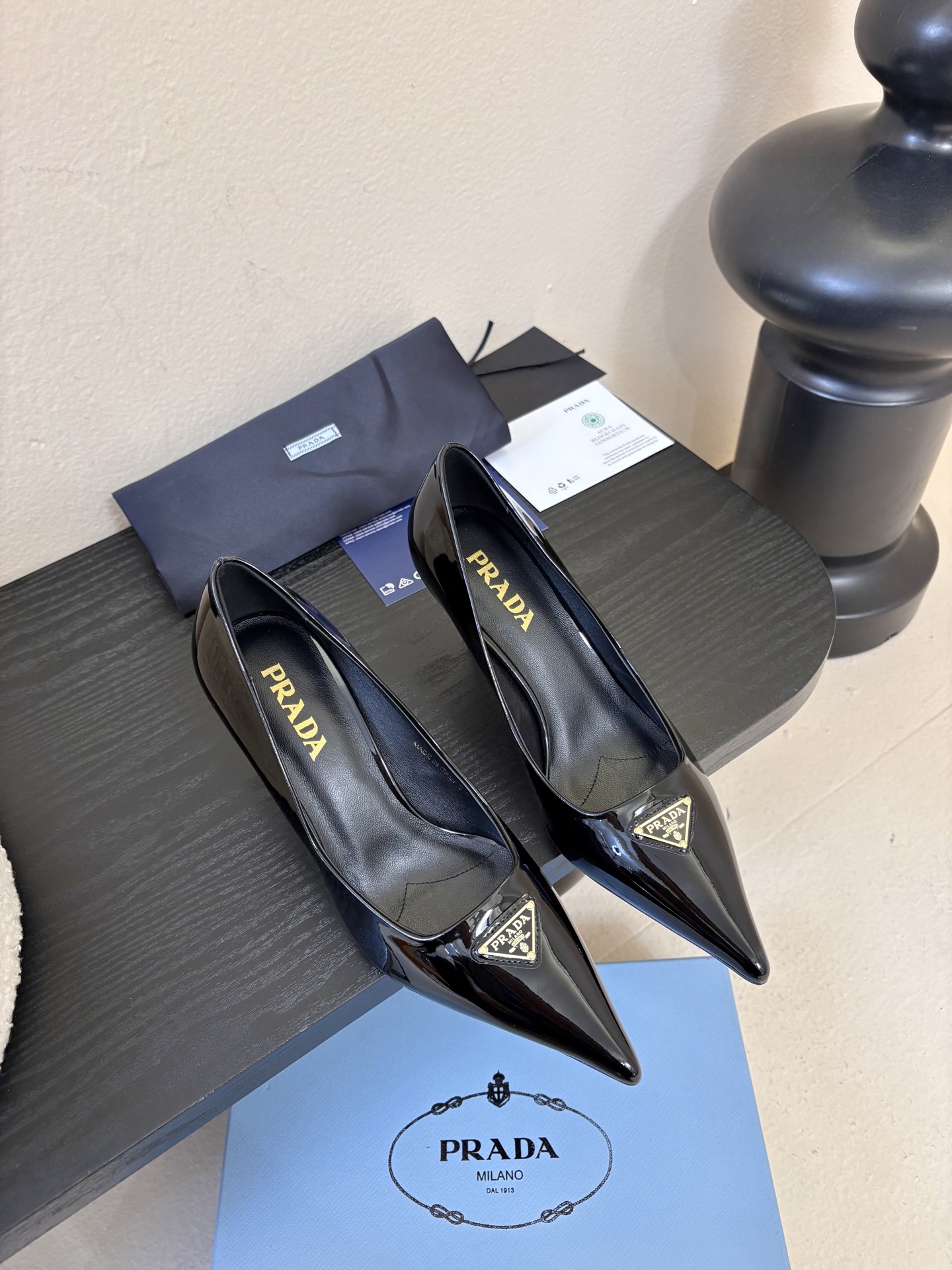 NO:696162,PRAD*25ss retro triangular pointed-toe kitten heel. The Prada triangle logo is embedded in the toe, which is a highly recognizable symbolic element of the brand and strengthens the visual memory point. The pointed-toe outline modifies the foot shape while adding an elegant and capable temperament, which is in line with Prada's consistent exquisite style. The thin strap design at the heel is both decorative and practical, which not only fixes the ankle, improves wearing stability, but also weakens the heavy feeling of high heels.  The heel height is moderate, creating an aura while ensuring walking comfort, suitable for the workplace or daily commuting scenes. The shoes are lined with leather, which is skin-friendly and breathable, reducing the stuffiness and friction discomfort caused by long-term wear. Patent leather upper, sheepskin lining, leather outsole, size 35-41 (customized sizes 40 and 41 are non-refundable), high-heeled shoes, prada, high heels, sheepskin, Leather soles19860909PRAD*25ss 复古三角标尖头小猫跟 鞋头处嵌入Prada三角徽标,这是品牌辨识度极高的符号元素,强化视觉记忆点.采用尖头轮廓,修饰脚型的同时增添优雅干练气质,契合Prada一贯的精致风格.后跟处的细带设计兼顾装饰性与实用性,既固定脚踝、提升穿着稳定性,又弱化高跟鞋的厚重感. 鞋跟高度适中,在营造气场的同时保障行走舒适度,适合职场或日常通勤场景.鞋内采用真皮衬里,亲肤透气,减少长时间穿着的闷热感与摩擦不适感. 鞋面漆皮 内里羊皮 大底真皮大底 size35-41码（40、41码定制不退换）,高跟鞋单鞋,prada,high heels,sheepskin,Leather soles,Women's Shoes