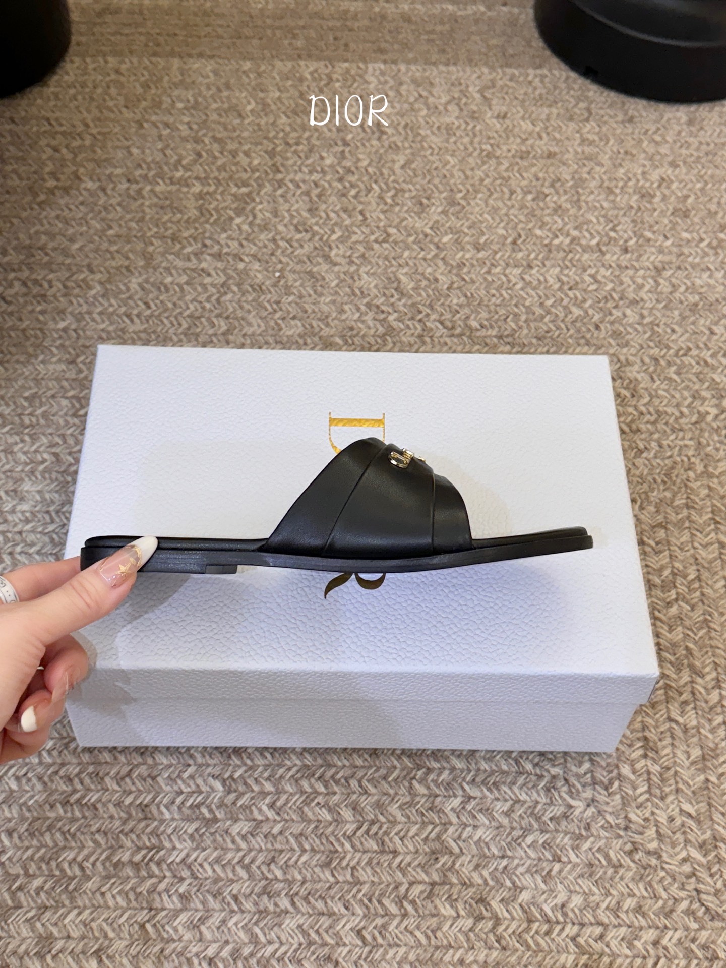 Dio* 新款CD标志平底拖鞋以简约优雅的设计重新诠释经典款式。鞋面精致的金色调叠层牛皮革饰带点缀以交叉