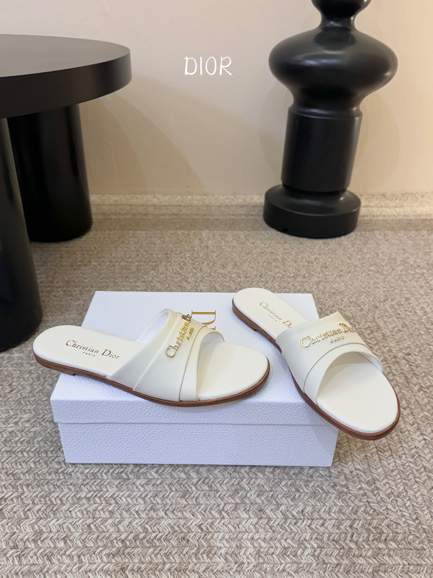 Dio* 新款CD标志平底拖鞋以简约优雅的设计重新诠释经典款式。鞋面精致的金色调叠层牛皮革饰带点缀以交叉