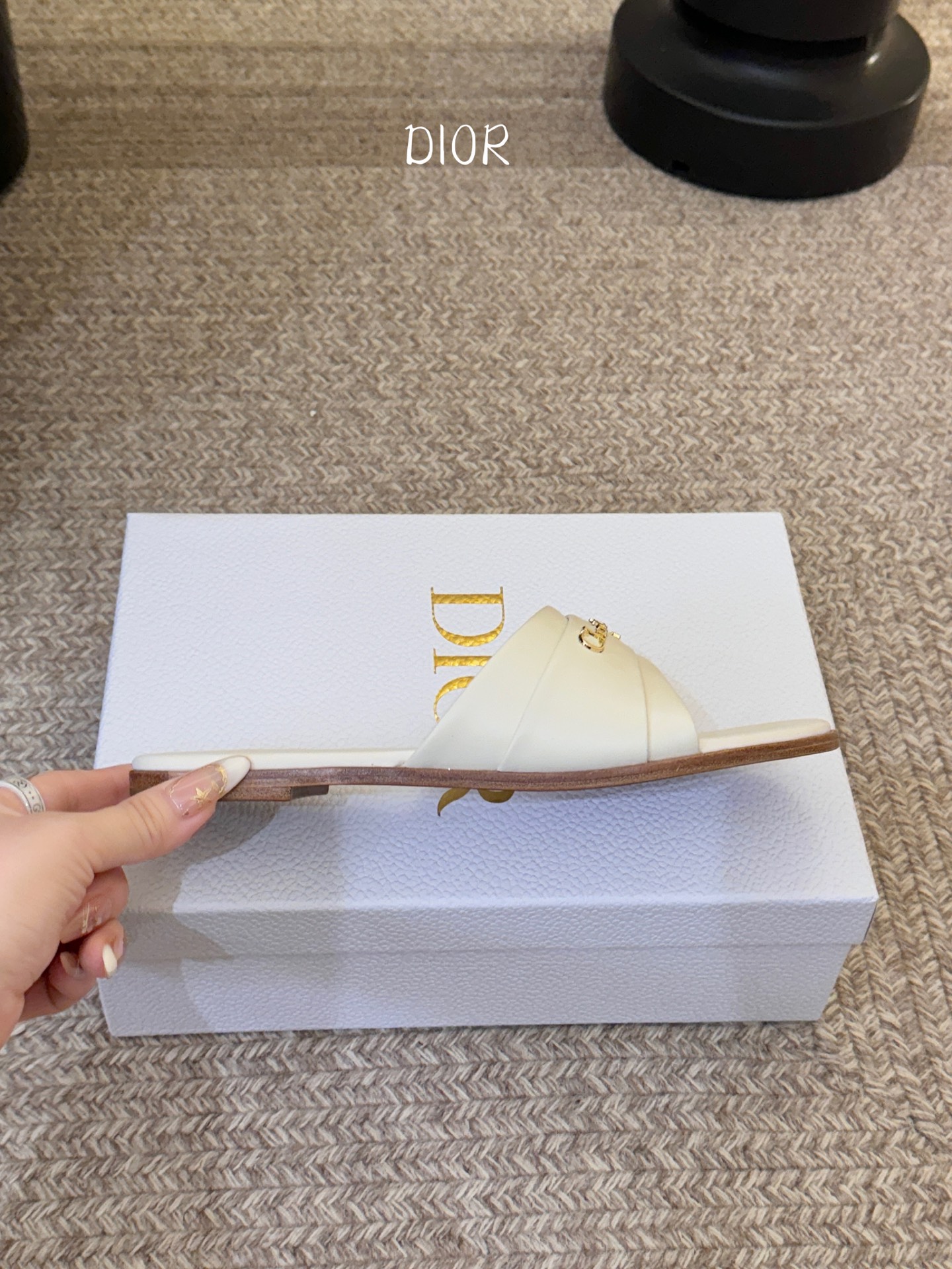 Dio* 新款CD标志平底拖鞋以简约优雅的设计重新诠释经典款式。鞋面精致的金色调叠层牛皮革饰带点缀以交叉