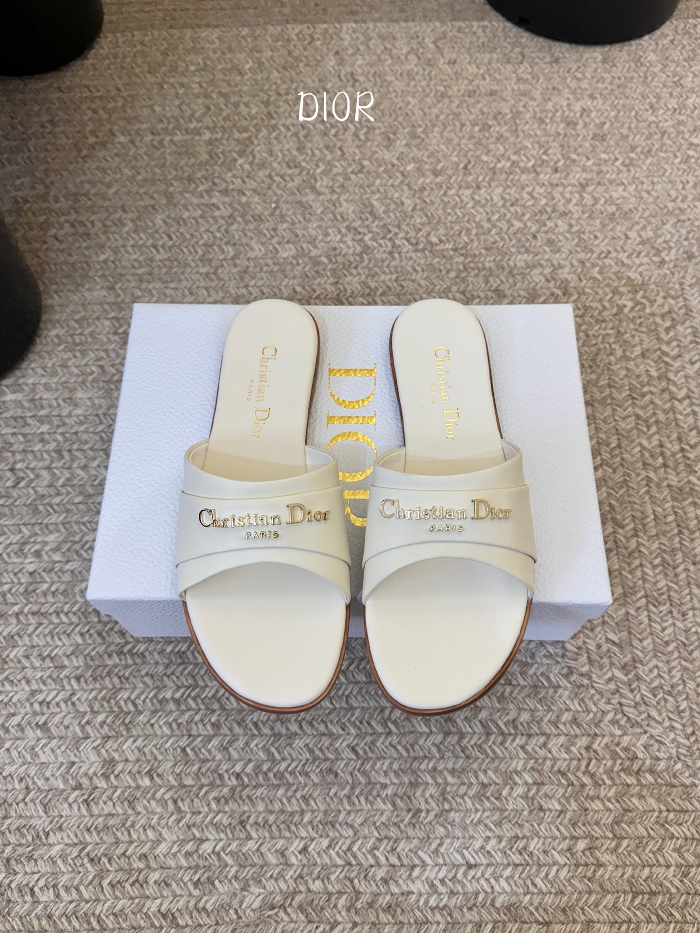 Dio* 新款CD标志平底拖鞋以简约优雅的设计重新诠释经典款式。鞋面精致的金色调叠层牛皮革饰带点缀以交叉