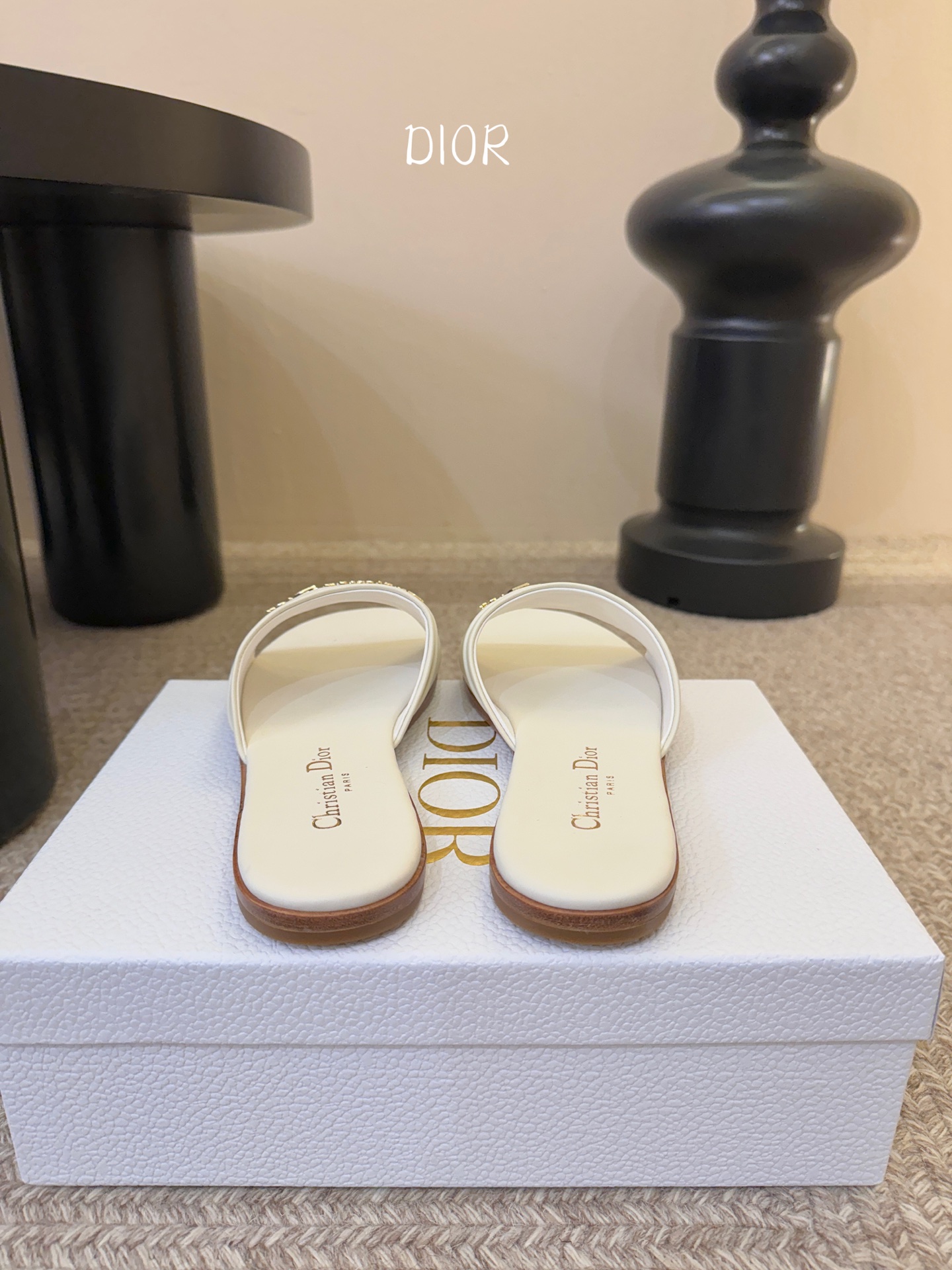 Dio* 新款CD标志平底拖鞋以简约优雅的设计重新诠释经典款式。鞋面精致的金色调叠层牛皮革饰带点缀以交叉