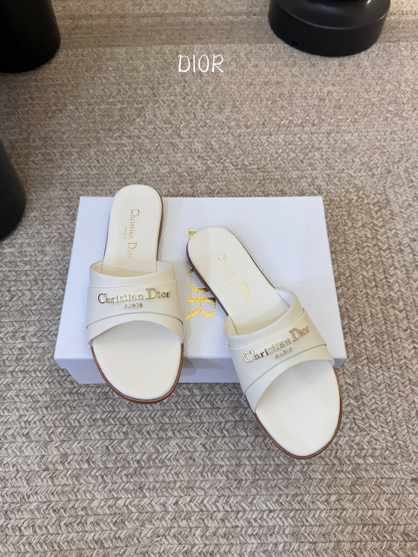 Dio* 新款CD标志平底拖鞋以简约优雅的设计重新诠释经典款式。鞋面精致的金色调叠层牛皮革饰带点缀以交叉