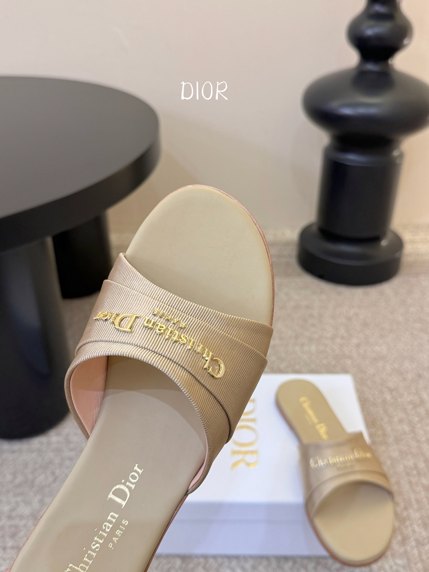 Dio* 新款CD标志平底拖鞋以简约优雅的设计重新诠释经典款式。鞋面精致的金色调叠层牛皮革饰带点缀以交叉