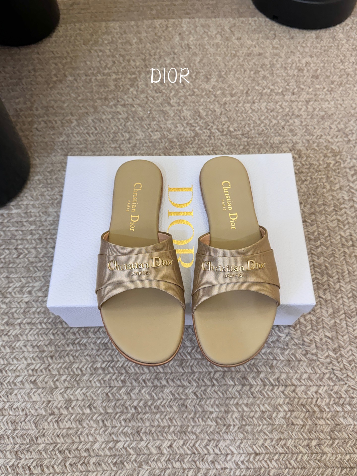 Dio* 新款CD标志平底拖鞋以简约优雅的设计重新诠释经典款式。鞋面精致的金色调叠层牛皮革饰带点缀以交叉