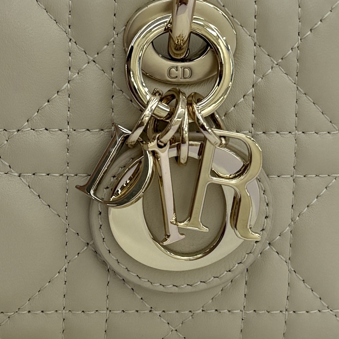 Lady D-Joy 手袋_ 编号: M0910_浅米色
这款 Lady D-Joy 超迷你手袋凸显 Lady Dior 系列的简约美学，集中体现了 Dior 对优雅和美丽的深刻洞见。采用浅米色羊皮革精心制作，饰以藤格纹缉面线，点缀以浅金色饰面金属 D.I.O.R. 吊饰提升格调，时髦典雅的设计经久不衰。搭配可拆卸的链条肩带和可调节、可拆卸的皮革肩带，可手提、肩背或斜挎，是日常或晚装造型的理想之选。
主体：羊皮革
里料：羊皮革
D.I.O.R. 吊饰
可拆卸链条肩带
可调节、可拆卸的皮革肩带
编号: S0910
意大利制造
尺寸：16 x 9 x 5 厘米（长 x 高 x 宽）
可收纳 1 部手机、1 个卡夹和唇膏
肩带长度：92 - 108 厘米
肩带顶端至手袋顶端长度：44 - 51 厘米
链条长度：46 厘米
链条顶端至手袋顶端长度：20 厘米
顶部手柄长度：18.5 厘米
顶部手柄顶端至手袋顶端长度：5.5 厘米
重量：400 克
尺寸和重量详情可能因产品材质而有所不同