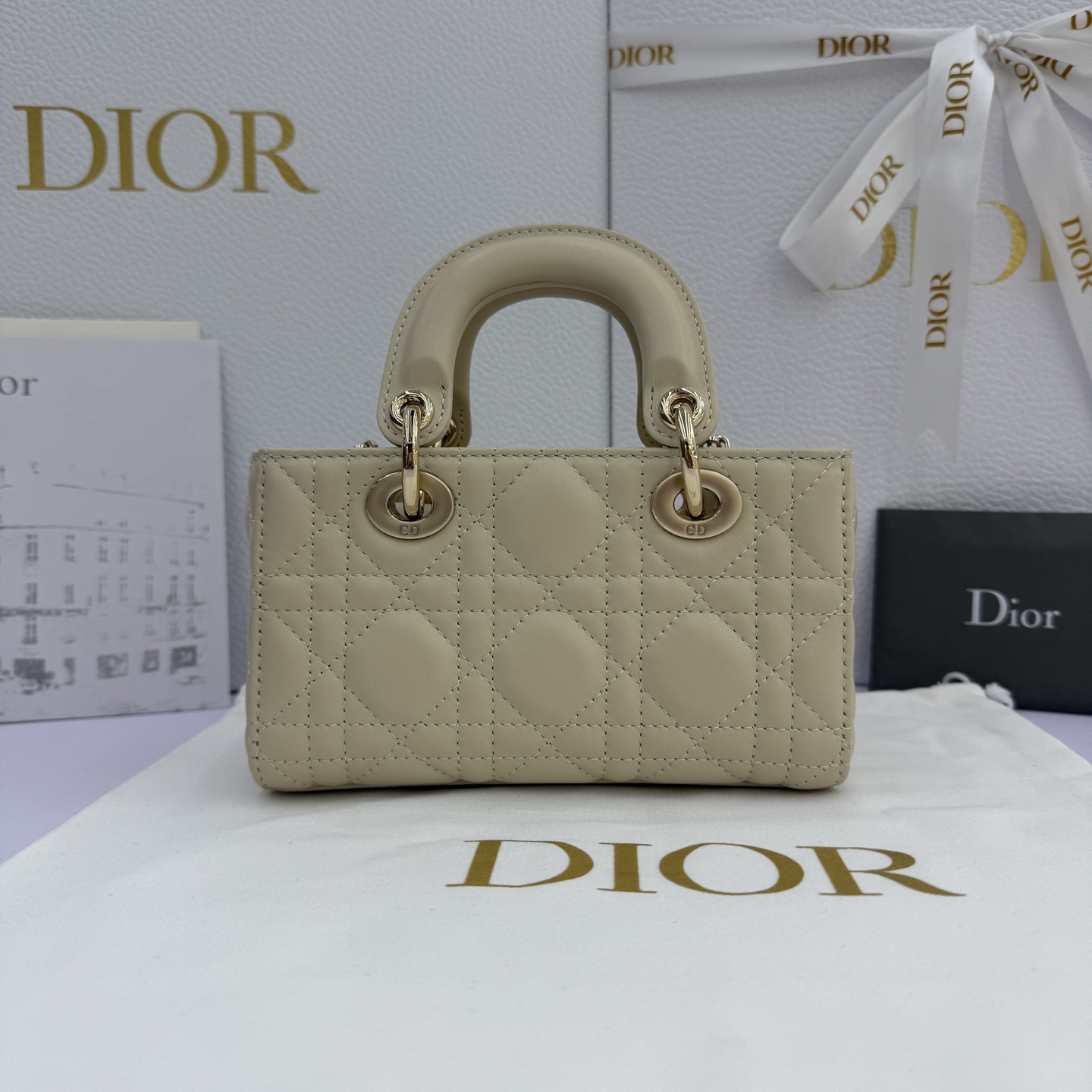 Lady D-Joy 手袋_ 编号: M0910_浅米色
这款 Lady D-Joy 超迷你手袋凸显 Lady Dior 系列的简约美学，集中体现了 Dior 对优雅和美丽的深刻洞见。采用浅米色羊皮革精心制作，饰以藤格纹缉面线，点缀以浅金色饰面金属 D.I.O.R. 吊饰提升格调，时髦典雅的设计经久不衰。搭配可拆卸的链条肩带和可调节、可拆卸的皮革肩带，可手提、肩背或斜挎，是日常或晚装造型的理想之选。
主体：羊皮革
里料：羊皮革
D.I.O.R. 吊饰
可拆卸链条肩带
可调节、可拆卸的皮革肩带
编号: S0910
意大利制造
尺寸：16 x 9 x 5 厘米（长 x 高 x 宽）
可收纳 1 部手机、1 个卡夹和唇膏
肩带长度：92 - 108 厘米
肩带顶端至手袋顶端长度：44 - 51 厘米
链条长度：46 厘米
链条顶端至手袋顶端长度：20 厘米
顶部手柄长度：18.5 厘米
顶部手柄顶端至手袋顶端长度：5.5 厘米
重量：400 克
尺寸和重量详情可能因产品材质而有所不同