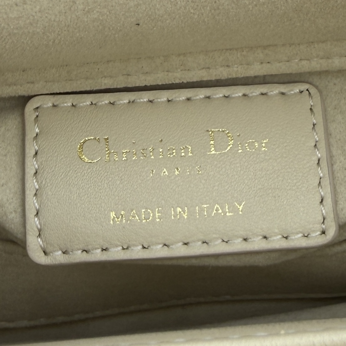 Lady D-Joy 手袋_ 编号: M0910_浅米色
这款 Lady D-Joy 超迷你手袋凸显 Lady Dior 系列的简约美学，集中体现了 Dior 对优雅和美丽的深刻洞见。采用浅米色羊皮革精心制作，饰以藤格纹缉面线，点缀以浅金色饰面金属 D.I.O.R. 吊饰提升格调，时髦典雅的设计经久不衰。搭配可拆卸的链条肩带和可调节、可拆卸的皮革肩带，可手提、肩背或斜挎，是日常或晚装造型的理想之选。
主体：羊皮革
里料：羊皮革
D.I.O.R. 吊饰
可拆卸链条肩带
可调节、可拆卸的皮革肩带
编号: S0910
意大利制造
尺寸：16 x 9 x 5 厘米（长 x 高 x 宽）
可收纳 1 部手机、1 个卡夹和唇膏
肩带长度：92 - 108 厘米
肩带顶端至手袋顶端长度：44 - 51 厘米
链条长度：46 厘米
链条顶端至手袋顶端长度：20 厘米
顶部手柄长度：18.5 厘米
顶部手柄顶端至手袋顶端长度：5.5 厘米
重量：400 克
尺寸和重量详情可能因产品材质而有所不同
