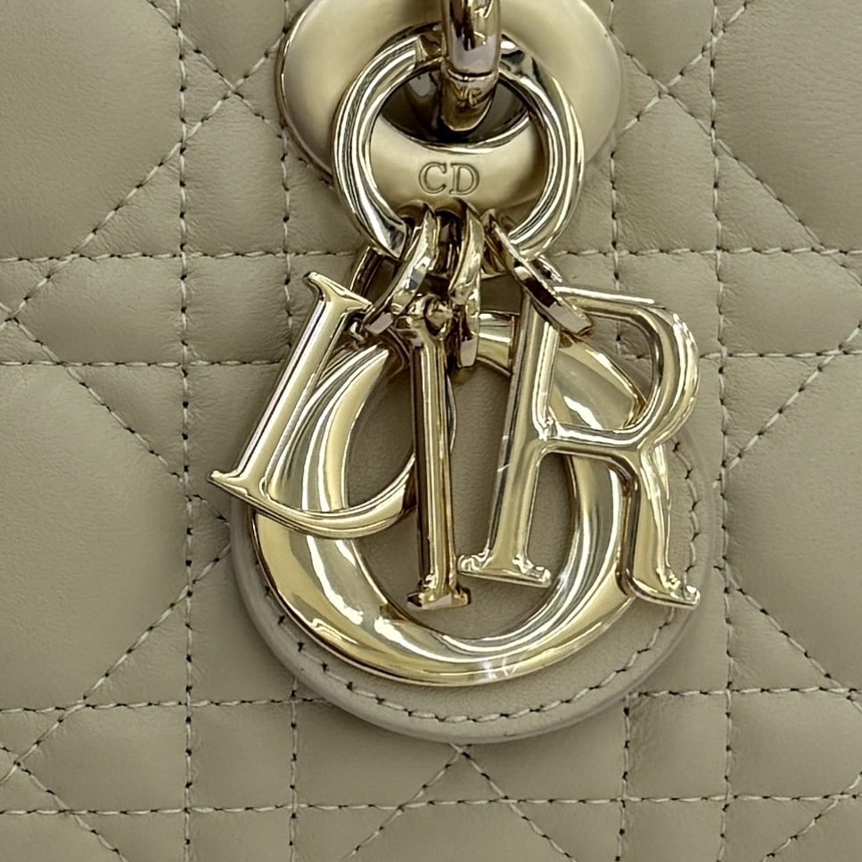 Lady D-Joy 手袋_ 款号：M0636_浅米色
这款 Lady D-Joy 手袋是二零二五秋冬成衣系列新品，凸显 Lady Dior 系列经典的简约美学，集中体现了 Dior 对典雅和美丽的深刻洞见。采用浅米色羊皮革精心制作，饰以藤格纹缉面线，时髦典雅的设计经久不衰。搭配浅金色饰面金属 D.I.O.R 吊饰提升格调，为精美的轮廓增添一分灵动。迷你款式，搭配可拆卸的链条肩带和可调节、可拆卸的皮革肩带，可手提、肩背或斜挎，是日常造型的理想之选。
主体：羊皮革里料:羊皮革可拆卸链条肩带可调节、可拆卸的皮革肩带
内部插袋
内含防尘袋
意大利制造
款号：M0636
尺寸：19&times;10.5&times;5.5厘米（长&times;高&times;宽）
可收纳1部手机、1个卡夹和唇膏
肩带长度：108-118.5 厘米
肩带顶端至手袋顶端长度：51.5-56.5 厘米
链条长度：54.5厘米
链条顶端至手袋顶端长度：24厘米
重量：660克
尺寸和重量详情可能因产品材质有所不同