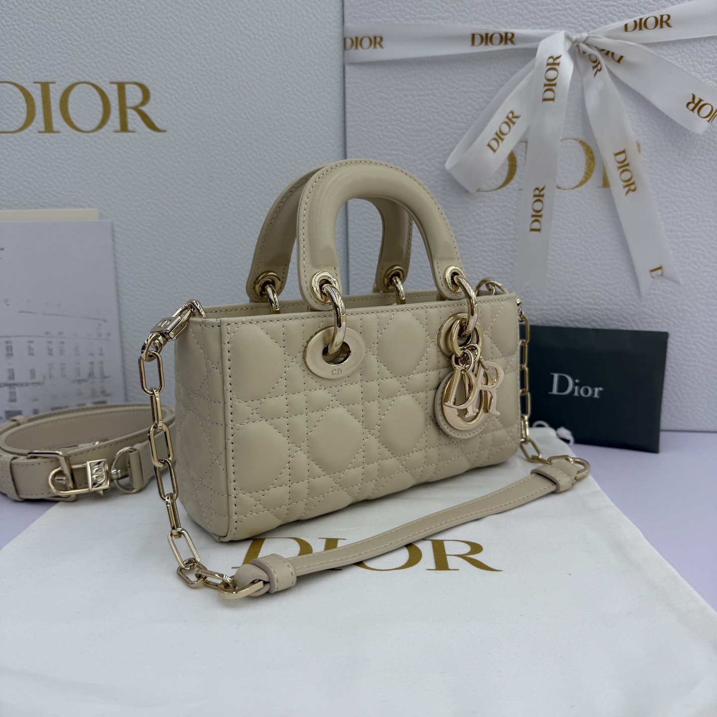 Lady D-Joy 手袋_ 款号：M0636_浅米色
这款 Lady D-Joy 手袋是二零二五秋冬成衣系列新品，凸显 Lady Dior 系列经典的简约美学，集中体现了 Dior 对典雅和美丽的深刻洞见。采用浅米色羊皮革精心制作，饰以藤格纹缉面线，时髦典雅的设计经久不衰。搭配浅金色饰面金属 D.I.O.R 吊饰提升格调，为精美的轮廓增添一分灵动。迷你款式，搭配可拆卸的链条肩带和可调节、可拆卸的皮革肩带，可手提、肩背或斜挎，是日常造型的理想之选。
主体：羊皮革里料:羊皮革可拆卸链条肩带可调节、可拆卸的皮革肩带
内部插袋
内含防尘袋
意大利制造
款号：M0636
尺寸：19&times;10.5&times;5.5厘米（长&times;高&times;宽）
可收纳1部手机、1个卡夹和唇膏
肩带长度：108-118.5 厘米
肩带顶端至手袋顶端长度：51.5-56.5 厘米
链条长度：54.5厘米
链条顶端至手袋顶端长度：24厘米
重量：660克
尺寸和重量详情可能因产品材质有所不同