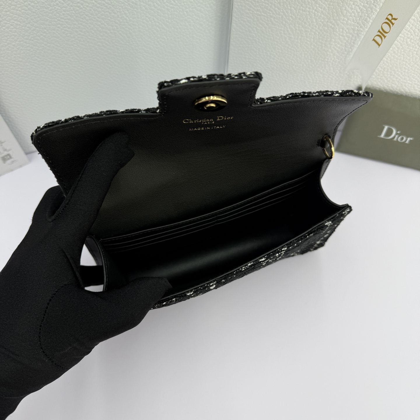 Dior Jolie 迷你鏈條手袋_編號:S3117_黑布
这款 Dior Jolie 迷你链条手袋是二零二五秋冬成衣系列新品，兼具优雅气质与实用功能。采用黑布羊皮革精心制作，搭配黑色藤格纹粗花呢等材质精心制作，翻盖饰以点缀白色树脂珠饰的复古金色饰面金属CD 标志。内设一个隔层，可收纳各种用品。搭配可调节、可拆卸CD链环肩带，穿插点缀以白色树脂珠饰，饰以皮革带，可搭配日常造型或晚装舒适手提、肩背或斜挎。 
主體:羊皮革，黑色藤格纹粗花
里料:羊皮革，科技面料 正面CD 扣环饰以白色树脂珠饰翻盖开合内部插袋6 个卡槽 饰以树脂珠饰和皮革带的可调节、可拆卸链条肩带内含防尘袋意大利制造 
尺寸：21cm&times;11.5cm&times;4.5cm 
编号：S3117