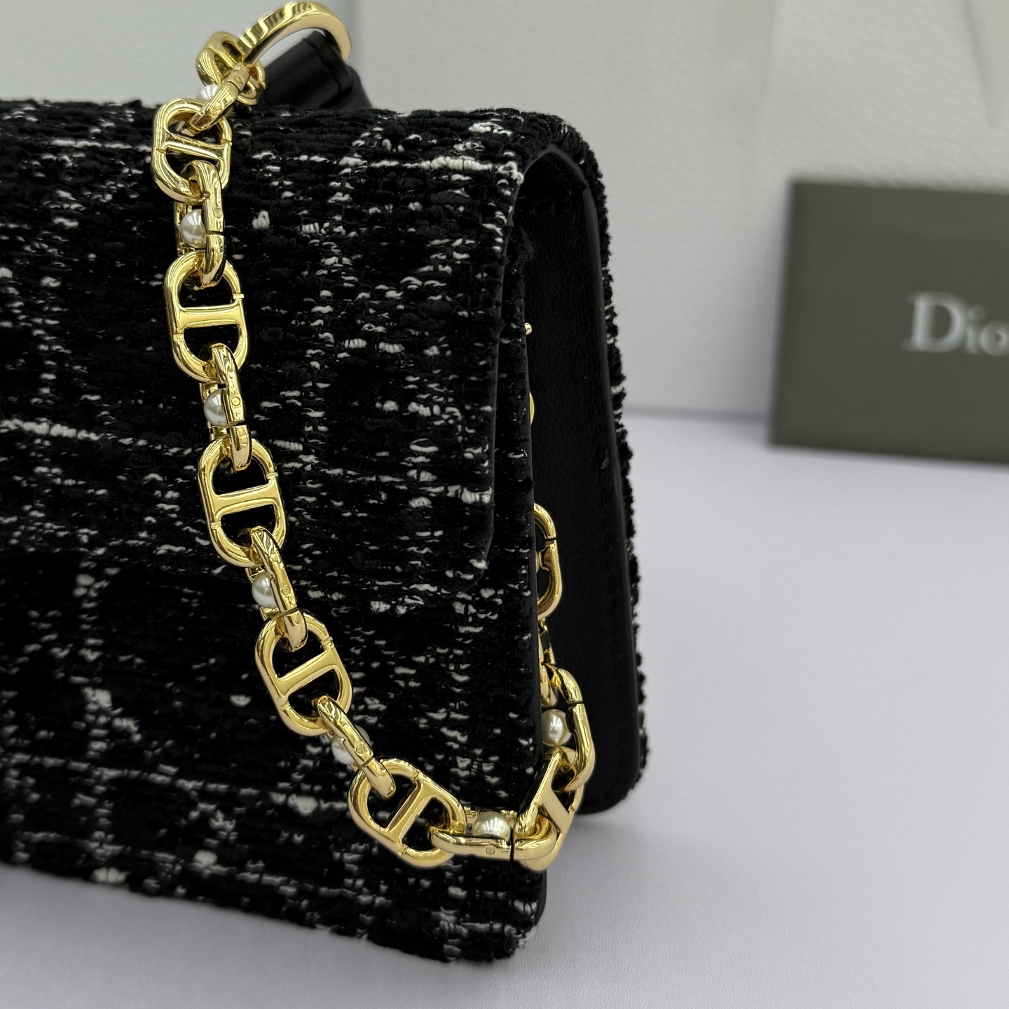 Dior Jolie 迷你鏈條手袋_編號:S3117_黑布
这款 Dior Jolie 迷你链条手袋是二零二五秋冬成衣系列新品，兼具优雅气质与实用功能。采用黑布羊皮革精心制作，搭配黑色藤格纹粗花呢等材质精心制作，翻盖饰以点缀白色树脂珠饰的复古金色饰面金属CD 标志。内设一个隔层，可收纳各种用品。搭配可调节、可拆卸CD链环肩带，穿插点缀以白色树脂珠饰，饰以皮革带，可搭配日常造型或晚装舒适手提、肩背或斜挎。 
主體:羊皮革，黑色藤格纹粗花
里料:羊皮革，科技面料 正面CD 扣环饰以白色树脂珠饰翻盖开合内部插袋6 个卡槽 饰以树脂珠饰和皮革带的可调节、可拆卸链条肩带内含防尘袋意大利制造 
尺寸：21cm&times;11.5cm&times;4.5cm 
编号：S3117