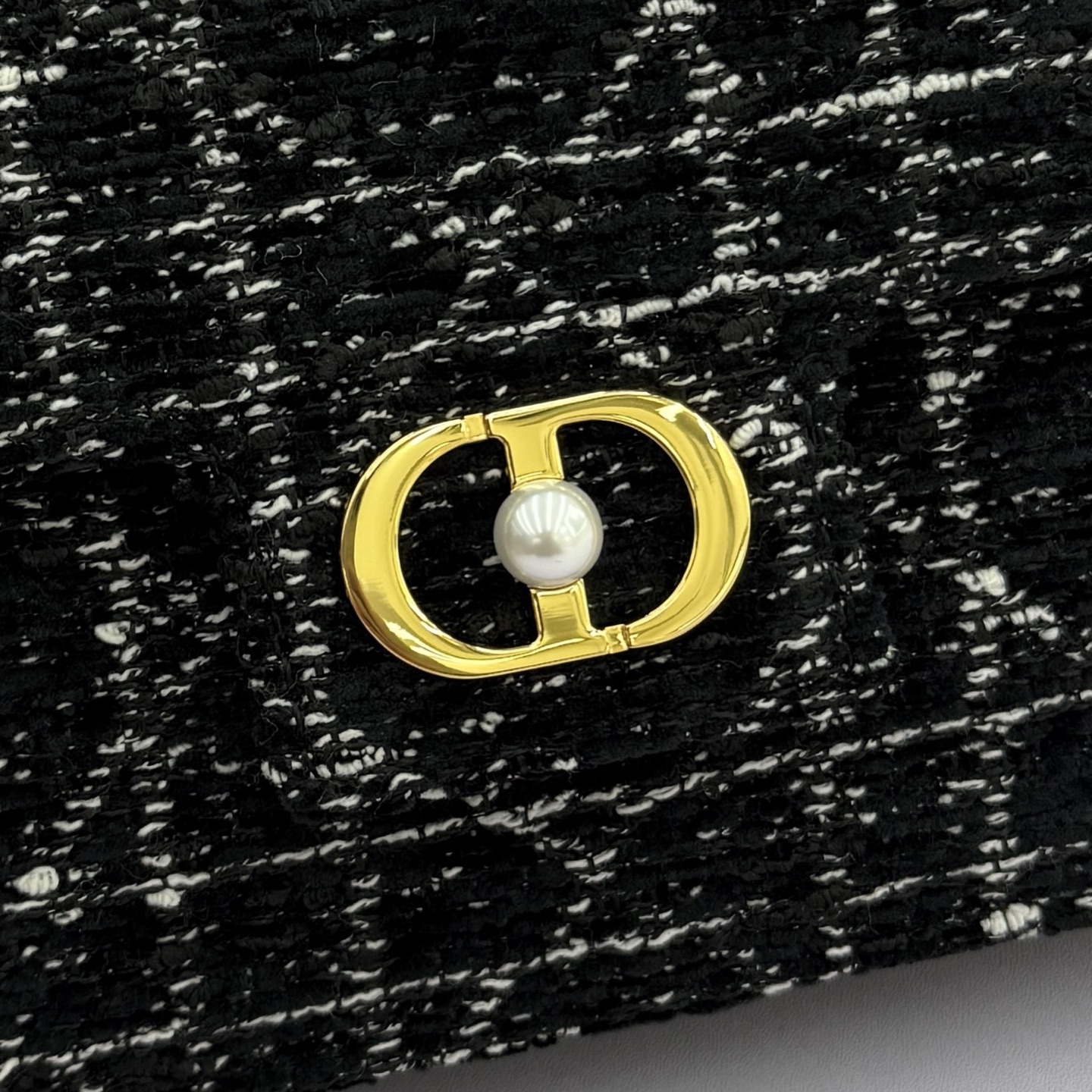 Dior Jolie 迷你鏈條手袋_編號:S3117_黑布
这款 Dior Jolie 迷你链条手袋是二零二五秋冬成衣系列新品，兼具优雅气质与实用功能。采用黑布羊皮革精心制作，搭配黑色藤格纹粗花呢等材质精心制作，翻盖饰以点缀白色树脂珠饰的复古金色饰面金属CD 标志。内设一个隔层，可收纳各种用品。搭配可调节、可拆卸CD链环肩带，穿插点缀以白色树脂珠饰，饰以皮革带，可搭配日常造型或晚装舒适手提、肩背或斜挎。 
主體:羊皮革，黑色藤格纹粗花
里料:羊皮革，科技面料 正面CD 扣环饰以白色树脂珠饰翻盖开合内部插袋6 个卡槽 饰以树脂珠饰和皮革带的可调节、可拆卸链条肩带内含防尘袋意大利制造 
尺寸：21cm&times;11.5cm&times;4.5cm 
编号：S3117