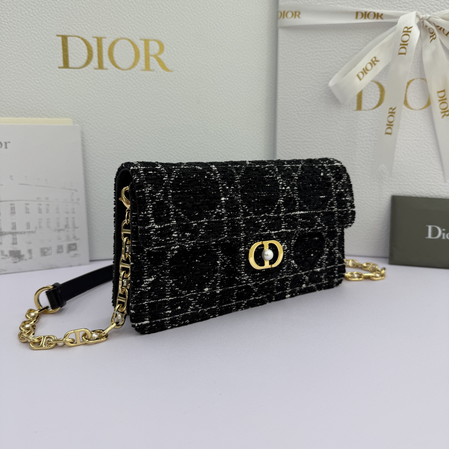 Dior Jolie 迷你鏈條手袋_編號:S3117_黑布
这款 Dior Jolie 迷你链条手袋是二零二五秋冬成衣系列新品，兼具优雅气质与实用功能。采用黑布羊皮革精心制作，搭配黑色藤格纹粗花呢等材质精心制作，翻盖饰以点缀白色树脂珠饰的复古金色饰面金属CD 标志。内设一个隔层，可收纳各种用品。搭配可调节、可拆卸CD链环肩带，穿插点缀以白色树脂珠饰，饰以皮革带，可搭配日常造型或晚装舒适手提、肩背或斜挎。 
主體:羊皮革，黑色藤格纹粗花
里料:羊皮革，科技面料 正面CD 扣环饰以白色树脂珠饰翻盖开合内部插袋6 个卡槽 饰以树脂珠饰和皮革带的可调节、可拆卸链条肩带内含防尘袋意大利制造 
尺寸：21cm&times;11.5cm&times;4.5cm 
编号：S3117