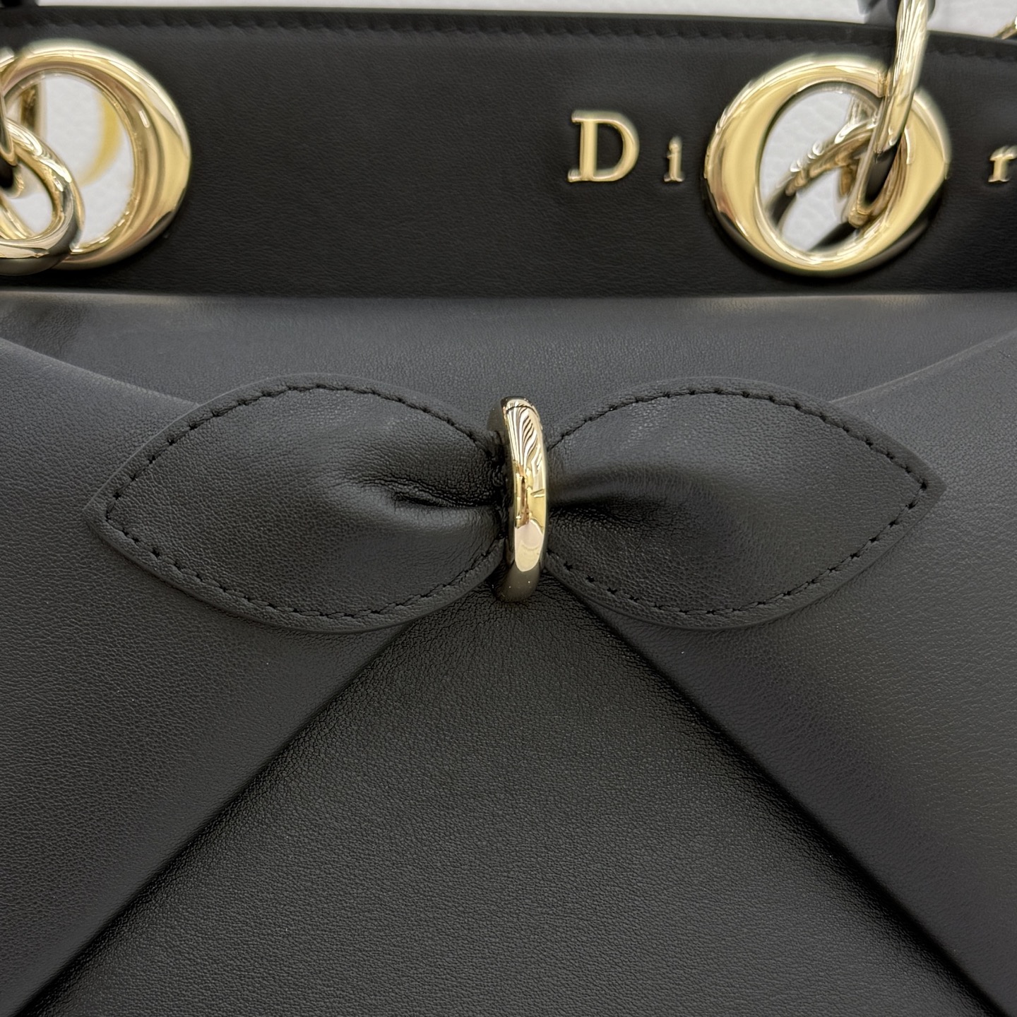 Dior 2026蝴蝶结手提包_编号0737_黑色金扣
🎀 Dior 2026 春夏新品#蝴蝶结手提包「黑色」
新设计的轮廓与造型，配色 丰富，适配多人！在夸张与优雅之间恰到好处！它的设计灵感源于迪奥先生设计的 Cigale礼服~立体的梯形包身+单手柄，造型自带优雅大气的腔调。包包的外观比较低调，几乎没有什么明显的大Logo。离近点再看，才发现原来Anderson把Dior字母Logo和包包提手的圆孔融合到了一起。
包包既有辨识度，也完全不是张扬挂的，整体散发着那种不动声色的高级感！值得一提的是，这款包还搭配了一条皮质长肩带。尤其出门旅行的时候就可以换上长肩带，既解放了双手，还衬得人轻松又随性~
型号：0737
尺寸：28*10*22（长*宽*高）