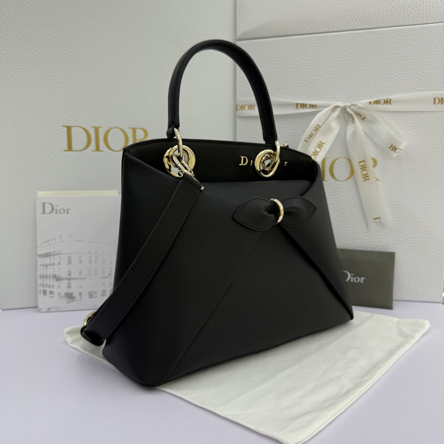 Dior 2026蝴蝶结手提包_编号0737_黑色金扣
🎀 Dior 2026 春夏新品#蝴蝶结手提包「黑色」
新设计的轮廓与造型，配色 丰富，适配多人！在夸张与优雅之间恰到好处！它的设计灵感源于迪奥先生设计的 Cigale礼服~立体的梯形包身+单手柄，造型自带优雅大气的腔调。包包的外观比较低调，几乎没有什么明显的大Logo。离近点再看，才发现原来Anderson把Dior字母Logo和包包提手的圆孔融合到了一起。
包包既有辨识度，也完全不是张扬挂的，整体散发着那种不动声色的高级感！值得一提的是，这款包还搭配了一条皮质长肩带。尤其出门旅行的时候就可以换上长肩带，既解放了双手，还衬得人轻松又随性~
型号：0737
尺寸：28*10*22（长*宽*高）