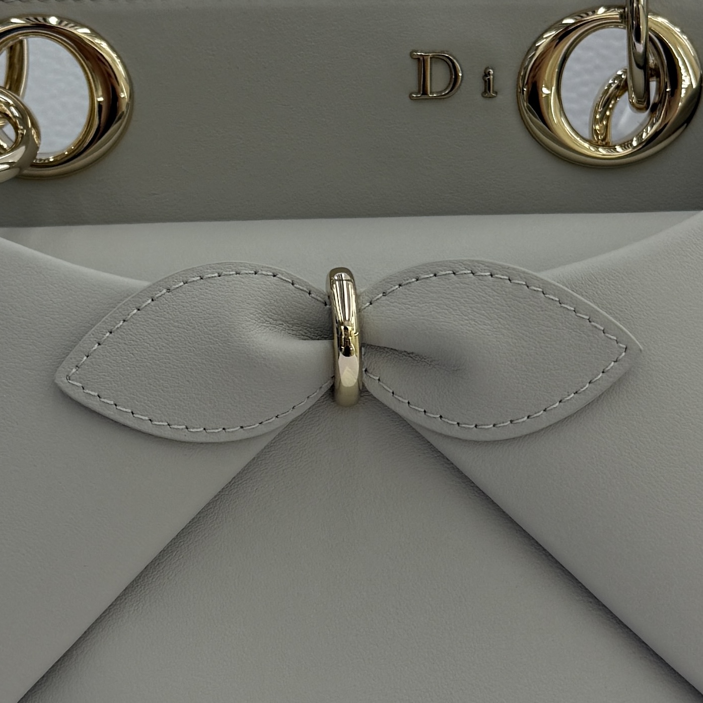 Dior 2026蝴蝶结手提包_编号7038_云雾灰金扣
🎀 Dior 2026 春夏新品#蝴蝶结手提包「云雾灰色」
新设计的轮廓与造型，配色 丰富，适配多人！在夸张与优雅之间恰到好处！它的设计灵感源于迪奥先生设计的 Cigale礼服~立体的梯形包身+单手柄，造型自带优雅大气的腔调。包包的外观比较低调，几乎没有什么明显的大Logo。离近点再看，才发现原来Anderson把Dior字母Logo和包包提手的圆孔融合到了一起。
包包既有辨识度，也完全不是张扬挂的，整体散发着那种不动声色的高级感！值得一提的是，这款包还搭配了一条皮质长肩带。尤其出门旅行的时候就可以换上长肩带，既解放了双手，还衬得人轻松又随性~
型号：7038
尺寸：28*10*22（长*宽*高）