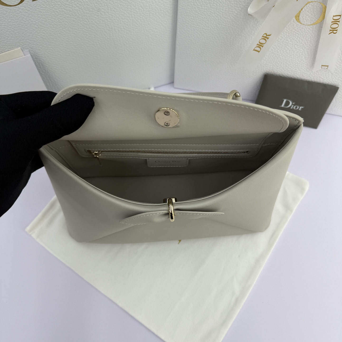 Dior 2026蝴蝶结手提包_编号7038_云雾灰金扣
🎀 Dior 2026 春夏新品#蝴蝶结手提包「云雾灰色」
新设计的轮廓与造型，配色 丰富，适配多人！在夸张与优雅之间恰到好处！它的设计灵感源于迪奥先生设计的 Cigale礼服~立体的梯形包身+单手柄，造型自带优雅大气的腔调。包包的外观比较低调，几乎没有什么明显的大Logo。离近点再看，才发现原来Anderson把Dior字母Logo和包包提手的圆孔融合到了一起。
包包既有辨识度，也完全不是张扬挂的，整体散发着那种不动声色的高级感！值得一提的是，这款包还搭配了一条皮质长肩带。尤其出门旅行的时候就可以换上长肩带，既解放了双手，还衬得人轻松又随性~
型号：7038
尺寸：28*10*22（长*宽*高）