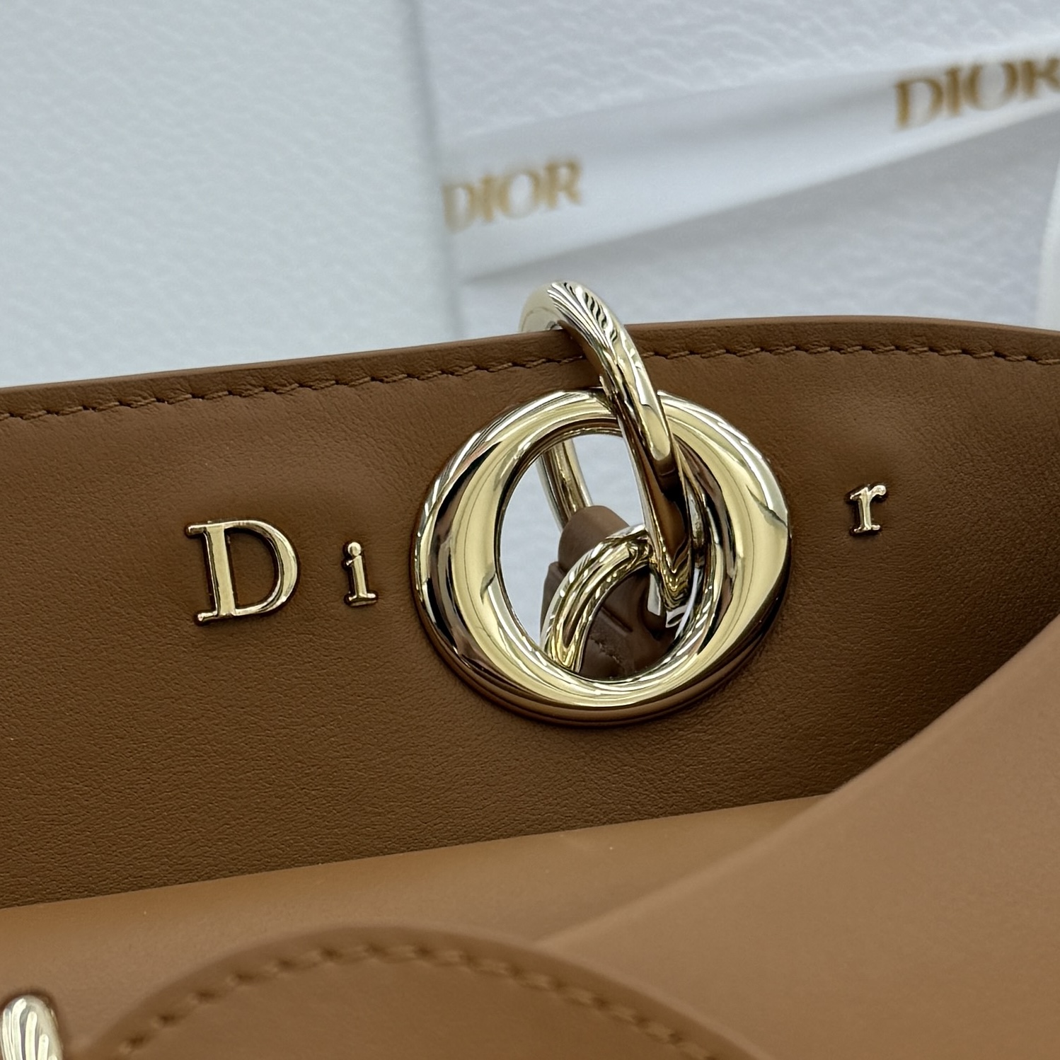 Dior 2026蝴蝶结手提包_编号7038_焦糖色金扣
🎀 Dior 2026 春夏新品#蝴蝶结手提包「焦糖色」
新设计的轮廓与造型，配色 丰富，适配多人！在夸张与优雅之间恰到好处！它的设计灵感源于迪奥先生设计的 Cigale礼服~立体的梯形包身+单手柄，造型自带优雅大气的腔调。包包的外观比较低调，几乎没有什么明显的大Logo。离近点再看，才发现原来Anderson把Dior字母Logo和包包提手的圆孔融合到了一起。
包包既有辨识度，也完全不是张扬挂的，整体散发着那种不动声色的高级感！值得一提的是，这款包还搭配了一条皮质长肩带。尤其出门旅行的时候就可以换上长肩带，既解放了双手，还衬得人轻松又随性~
型号：7038
尺寸：28*10*22（长*宽*高）