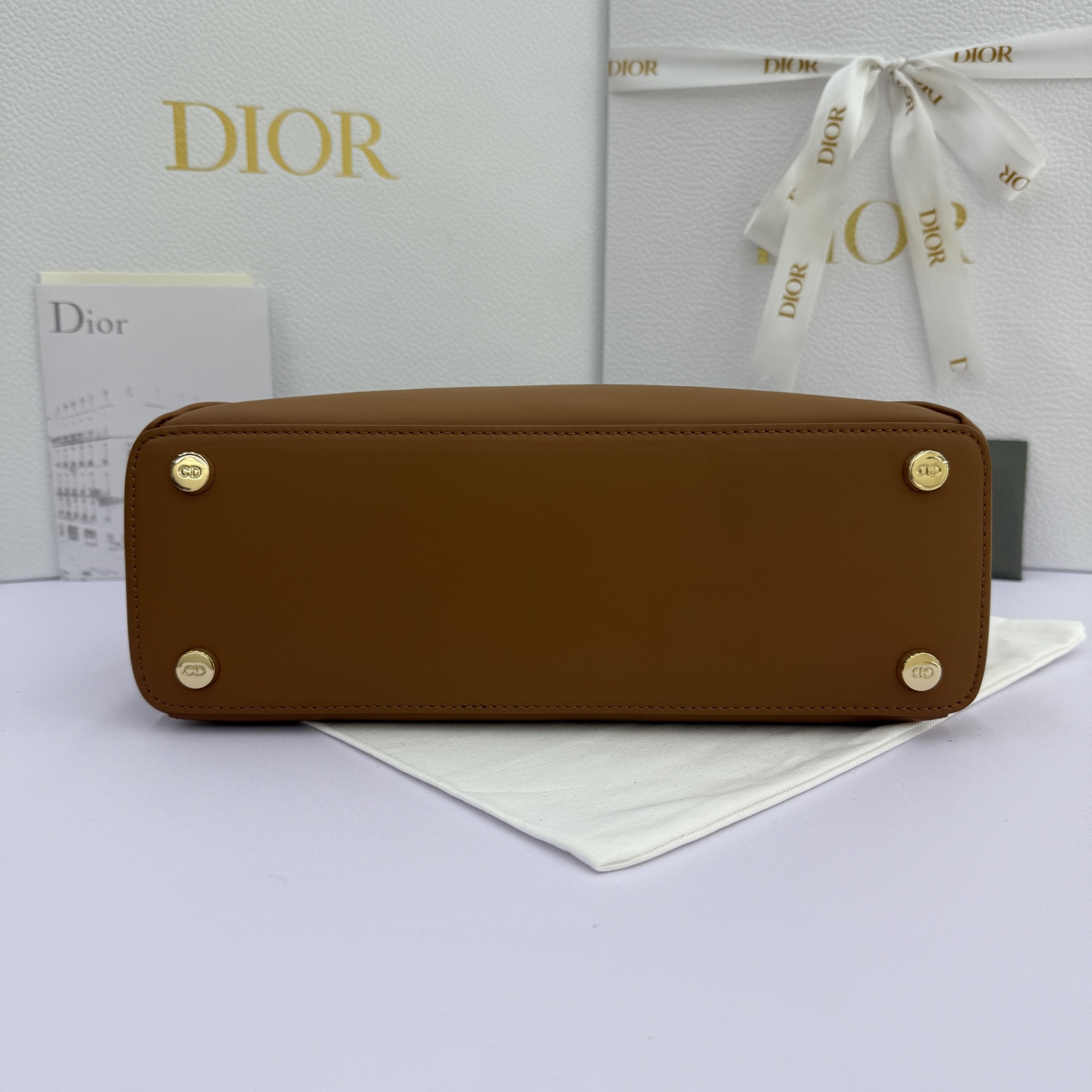 Dior 2026蝴蝶结手提包_编号7038_焦糖色金扣
🎀 Dior 2026 春夏新品#蝴蝶结手提包「焦糖色」
新设计的轮廓与造型，配色 丰富，适配多人！在夸张与优雅之间恰到好处！它的设计灵感源于迪奥先生设计的 Cigale礼服~立体的梯形包身+单手柄，造型自带优雅大气的腔调。包包的外观比较低调，几乎没有什么明显的大Logo。离近点再看，才发现原来Anderson把Dior字母Logo和包包提手的圆孔融合到了一起。
包包既有辨识度，也完全不是张扬挂的，整体散发着那种不动声色的高级感！值得一提的是，这款包还搭配了一条皮质长肩带。尤其出门旅行的时候就可以换上长肩带，既解放了双手，还衬得人轻松又随性~
型号：7038
尺寸：28*10*22（长*宽*高）