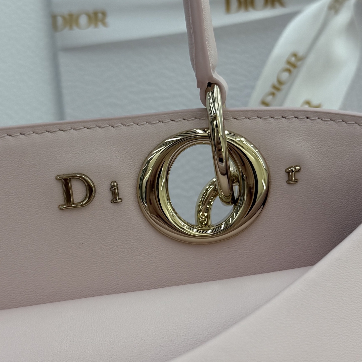 Dior 2026蝴蝶结手提包_编号7038_淡粉色金扣
🎀 Dior 2026 春夏新品#蝴蝶结手提包「淡粉色」
新设计的轮廓与造型，配色 丰富，适配多人！在夸张与优雅之间恰到好处！它的设计灵感源于迪奥先生设计的 Cigale礼服~立体的梯形包身+单手柄，造型自带优雅大气的腔调。包包的外观比较低调，几乎没有什么明显的大Logo。离近点再看，才发现原来Anderson把Dior字母Logo和包包提手的圆孔融合到了一起。
包包既有辨识度，也完全不是张扬挂的，整体散发着那种不动声色的高级感！值得一提的是，这款包还搭配了一条皮质长肩带。尤其出门旅行的时候就可以换上长肩带，既解放了双手，还衬得人轻松又随性~
型号：7038
尺寸：28*10*22（长*宽*高）