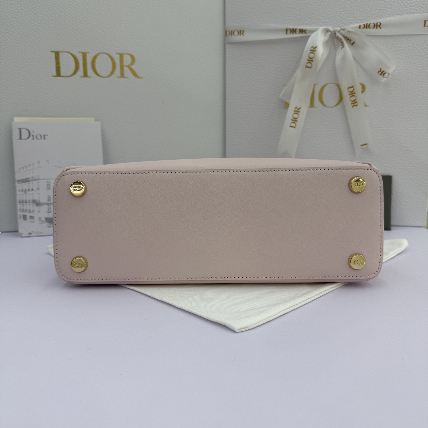 Dior 2026蝴蝶结手提包_编号7038_淡粉色金扣
🎀 Dior 2026 春夏新品#蝴蝶结手提包「淡粉色」
新设计的轮廓与造型，配色 丰富，适配多人！在夸张与优雅之间恰到好处！它的设计灵感源于迪奥先生设计的 Cigale礼服~立体的梯形包身+单手柄，造型自带优雅大气的腔调。包包的外观比较低调，几乎没有什么明显的大Logo。离近点再看，才发现原来Anderson把Dior字母Logo和包包提手的圆孔融合到了一起。
包包既有辨识度，也完全不是张扬挂的，整体散发着那种不动声色的高级感！值得一提的是，这款包还搭配了一条皮质长肩带。尤其出门旅行的时候就可以换上长肩带，既解放了双手，还衬得人轻松又随性~
型号：7038
尺寸：28*10*22（长*宽*高）
