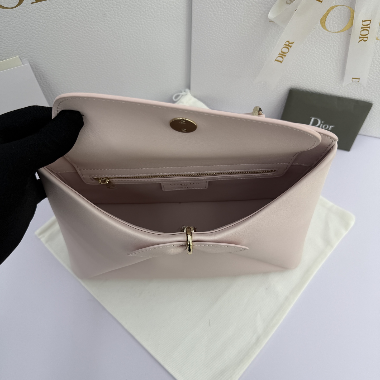 Dior 2026蝴蝶结手提包_编号7038_淡粉色金扣
🎀 Dior 2026 春夏新品#蝴蝶结手提包「淡粉色」
新设计的轮廓与造型，配色 丰富，适配多人！在夸张与优雅之间恰到好处！它的设计灵感源于迪奥先生设计的 Cigale礼服~立体的梯形包身+单手柄，造型自带优雅大气的腔调。包包的外观比较低调，几乎没有什么明显的大Logo。离近点再看，才发现原来Anderson把Dior字母Logo和包包提手的圆孔融合到了一起。
包包既有辨识度，也完全不是张扬挂的，整体散发着那种不动声色的高级感！值得一提的是，这款包还搭配了一条皮质长肩带。尤其出门旅行的时候就可以换上长肩带，既解放了双手，还衬得人轻松又随性~
型号：7038
尺寸：28*10*22（长*宽*高）