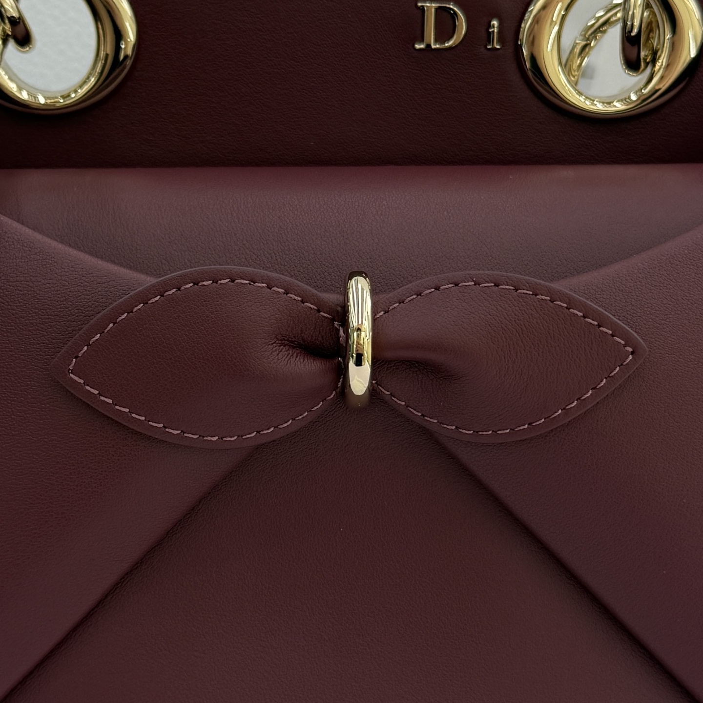 Dior 2026蝴蝶结手提包_编号7038_酒红色金扣
🎀 Dior 2026 春夏新品#蝴蝶结手提包「酒红色」
新设计的轮廓与造型，配色 丰富，适配多人！在夸张与优雅之间恰到好处！它的设计灵感源于迪奥先生设计的 Cigale礼服~立体的梯形包身+单手柄，造型自带优雅大气的腔调。包包的外观比较低调，几乎没有什么明显的大Logo。离近点再看，才发现原来Anderson把Dior字母Logo和包包提手的圆孔融合到了一起。
包包既有辨识度，也完全不是张扬挂的，整体散发着那种不动声色的高级感！值得一提的是，这款包还搭配了一条皮质长肩带。尤其出门旅行的时候就可以换上长肩带，既解放了双手，还衬得人轻松又随性~
型号：7038
尺寸：28*10*22（长*宽*高）