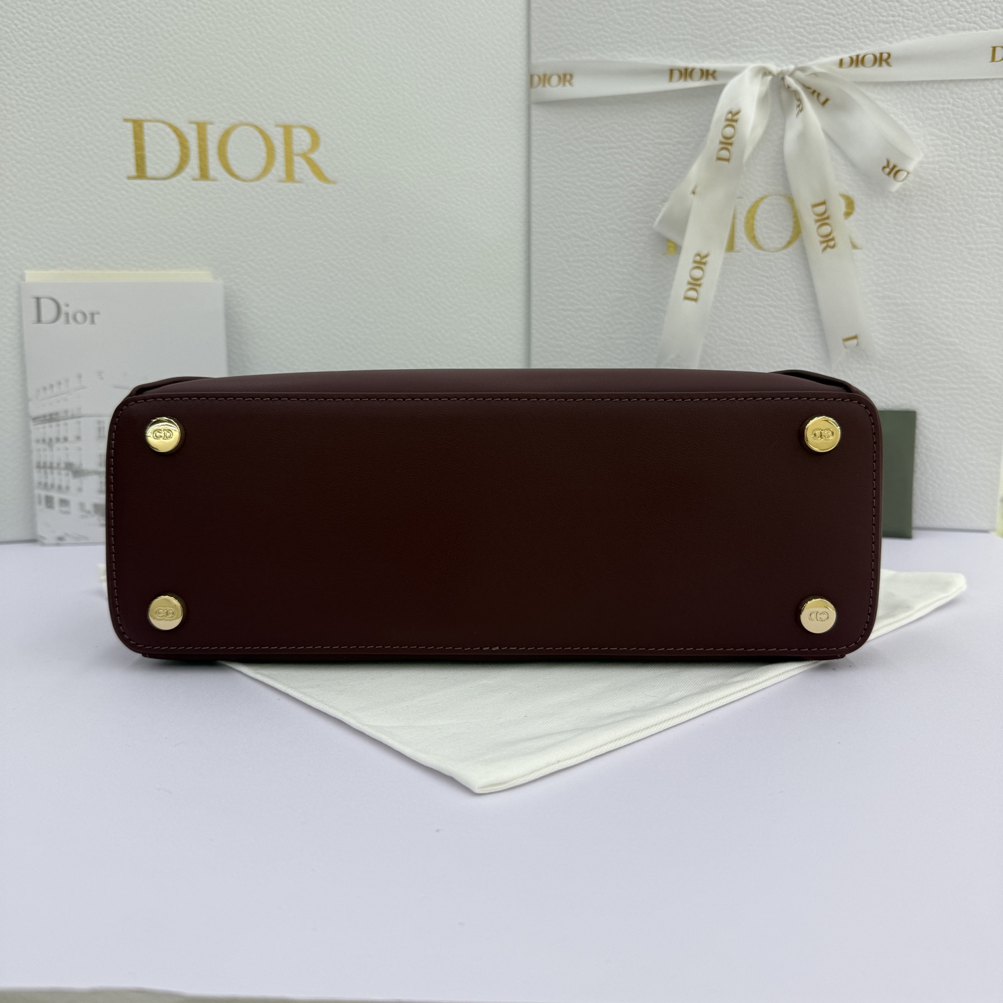 Dior 2026蝴蝶结手提包_编号7038_酒红色金扣
🎀 Dior 2026 春夏新品#蝴蝶结手提包「酒红色」
新设计的轮廓与造型，配色 丰富，适配多人！在夸张与优雅之间恰到好处！它的设计灵感源于迪奥先生设计的 Cigale礼服~立体的梯形包身+单手柄，造型自带优雅大气的腔调。包包的外观比较低调，几乎没有什么明显的大Logo。离近点再看，才发现原来Anderson把Dior字母Logo和包包提手的圆孔融合到了一起。
包包既有辨识度，也完全不是张扬挂的，整体散发着那种不动声色的高级感！值得一提的是，这款包还搭配了一条皮质长肩带。尤其出门旅行的时候就可以换上长肩带，既解放了双手，还衬得人轻松又随性~
型号：7038
尺寸：28*10*22（长*宽*高）