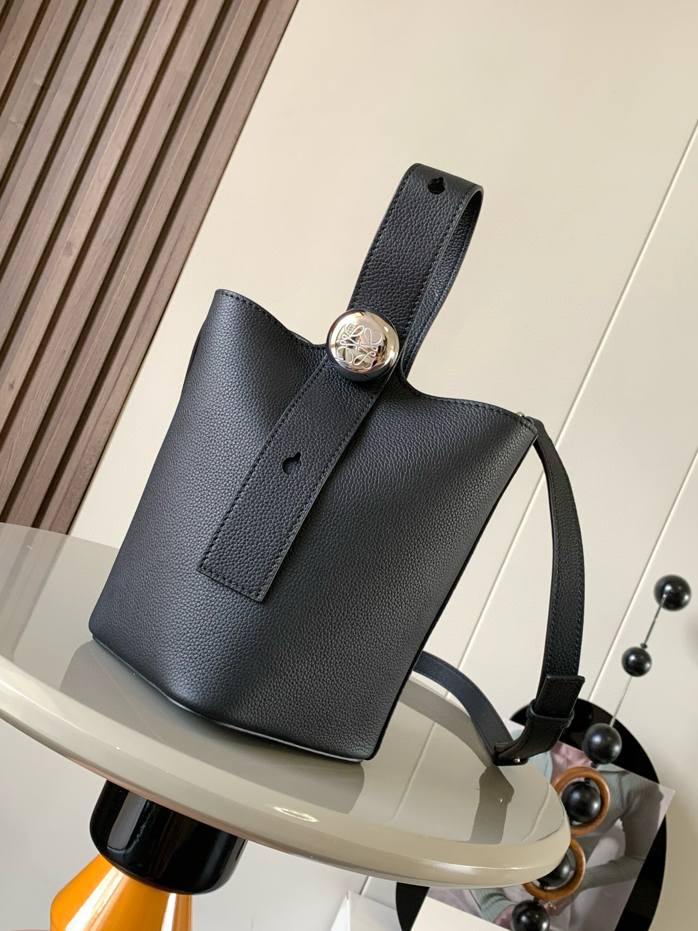 NO:208347,Mini Soft Grain Cowhide Leather Pebble Bucket Handbag Pebble cleverly combines pure simple lines with eye-catching design style to create a unique and innovative handbag design. The iconic Anagram engraving hardware combines decorative and practical functions, adjusts the length of the shoulder strap and is suitable for a variety of carrying methods. The unique twisted structure complements the delicate details. This mini version is made of soft grain cowhide. It can be cross-body, shoulder or hand-held * Adjustable removable shoulder strap * Magnetic buckle opening and closing * Inner bag * Synthetic leather lining * Anagram engraving pebble Model number 9047 Color black lying Size 20CM~16CM~16CM, Loewe, cowhide19860909迷你柔软粒面牛皮革 Pebble Bucket 水桶手袋Pebble将纯粹的简约线条与瞩目设计风格巧妙融合造就别具一格的创新的手袋设计.标志性的 Anagram 雕刻五金件兼具装饰和实用功能,可调节肩带长度并适合多种携带方式,独特的扭曲结构与微妙的细节相得益彰.此迷你版本采用柔软粒面牛皮革制成.可斜挎、肩背或手提＊可调节可拆卸肩带＊磁扣开合＊内袋＊合成革衬里* Anagram 雕刻卵石 款号9047 颜色黑色荔 尺寸20CM～16CM～16CM,罗意威,loewe,cowhide,Bag